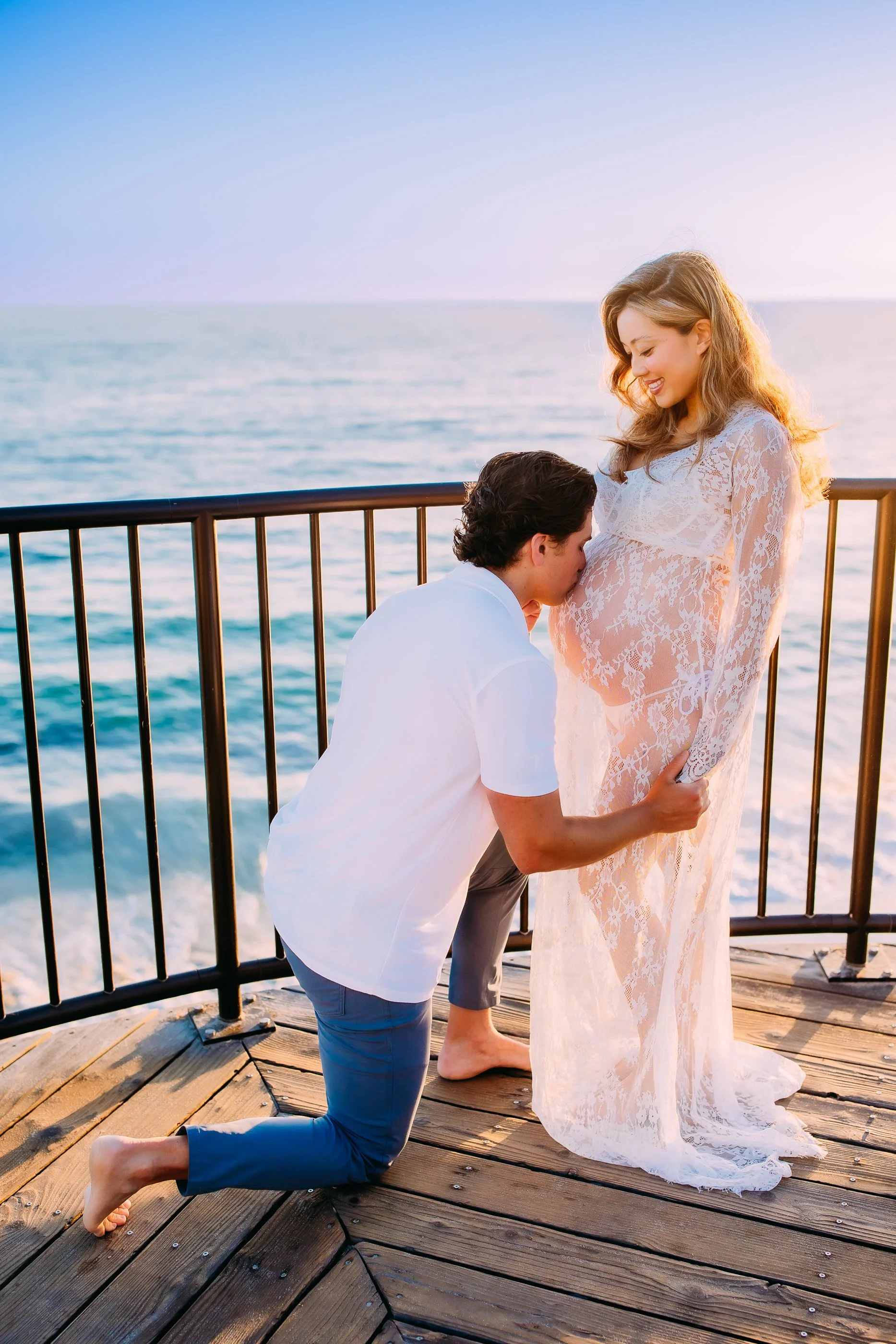 husband kissing his pregnant wife's belly during their sunset maternity photoshoot in Laguna Beach, California