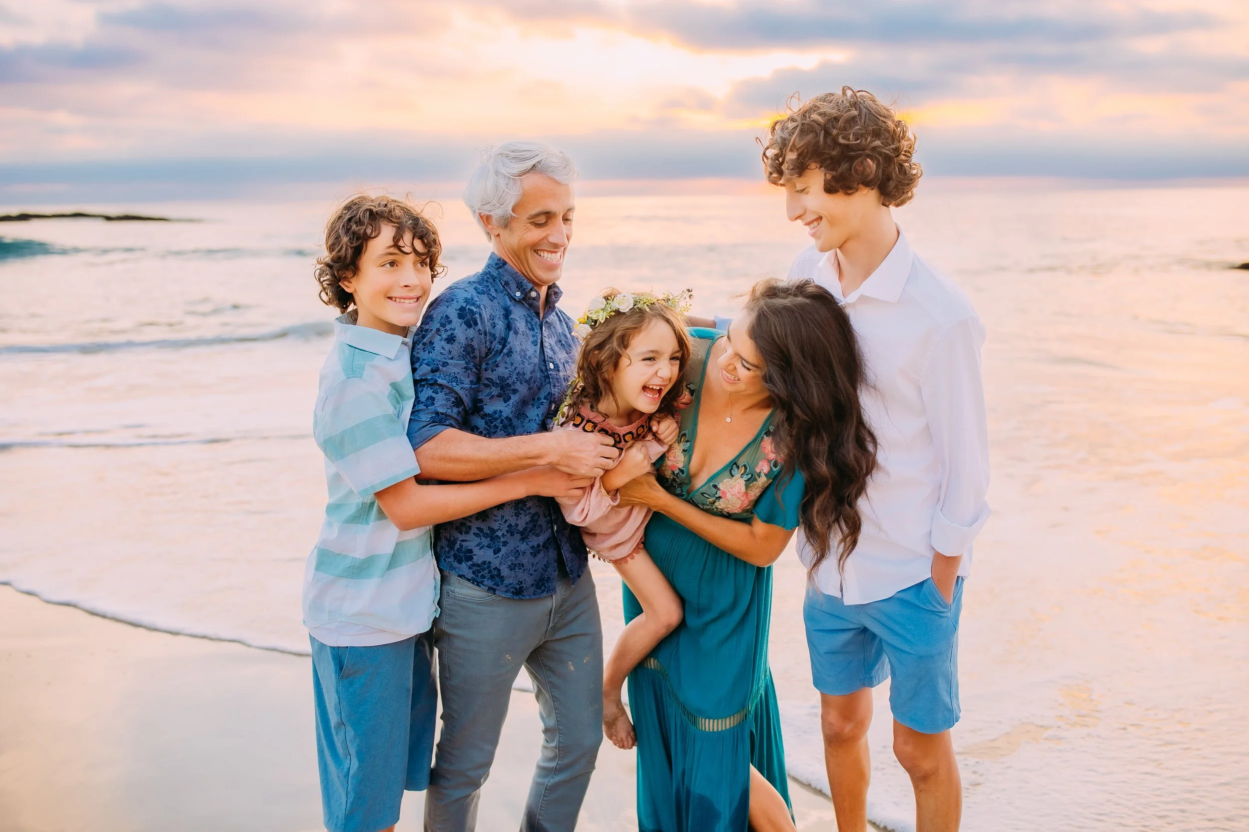 family tickling their little sister during their beach photoshoot in Newport Beach, California