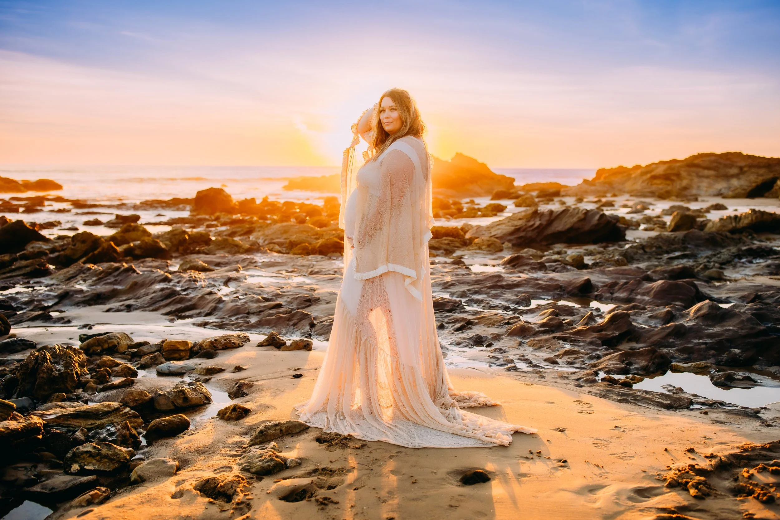Pregnant mom posing and looking into the camera at her Newport Beach photoshoot at sunset