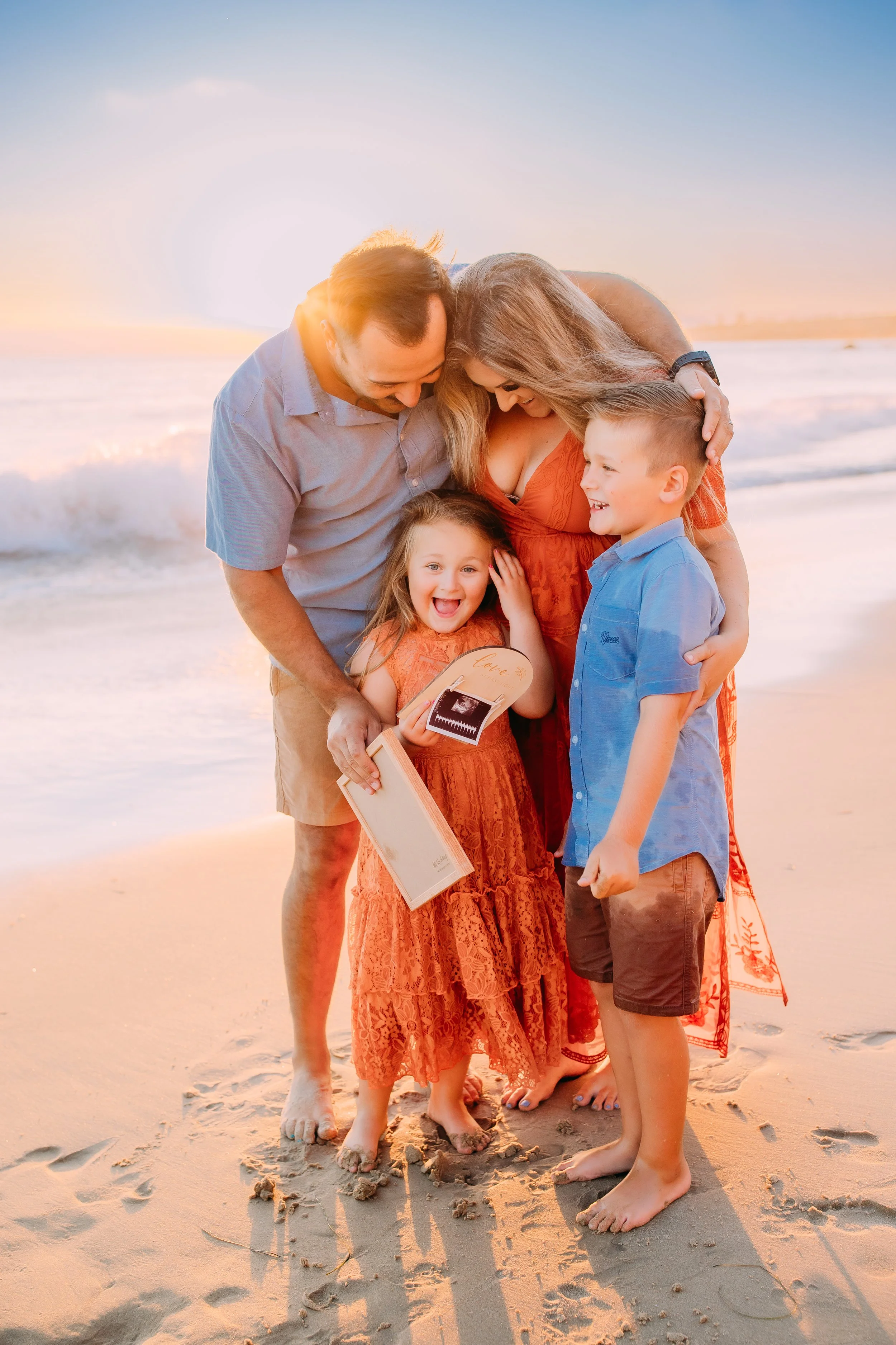 brother and sister laughing about the news of the new baby sibling during their sunset photoshoot in Newport Beach, California