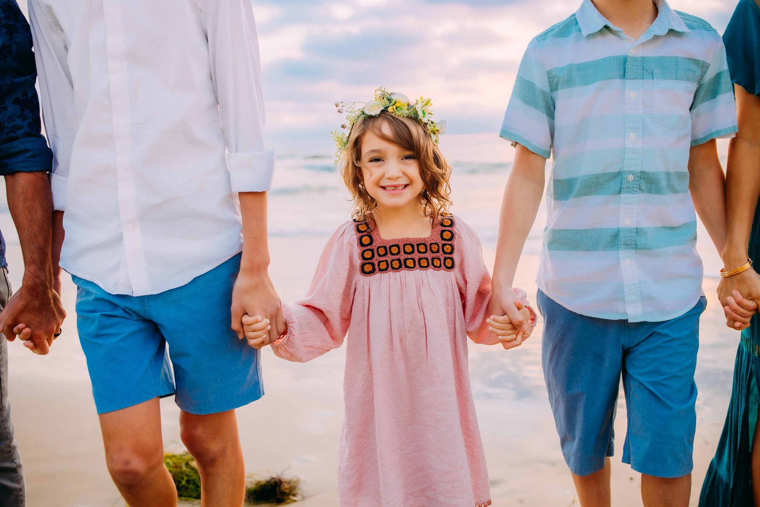 little girl smiling at the camera while at the ocean during her family photo session in Newport Beach, California
