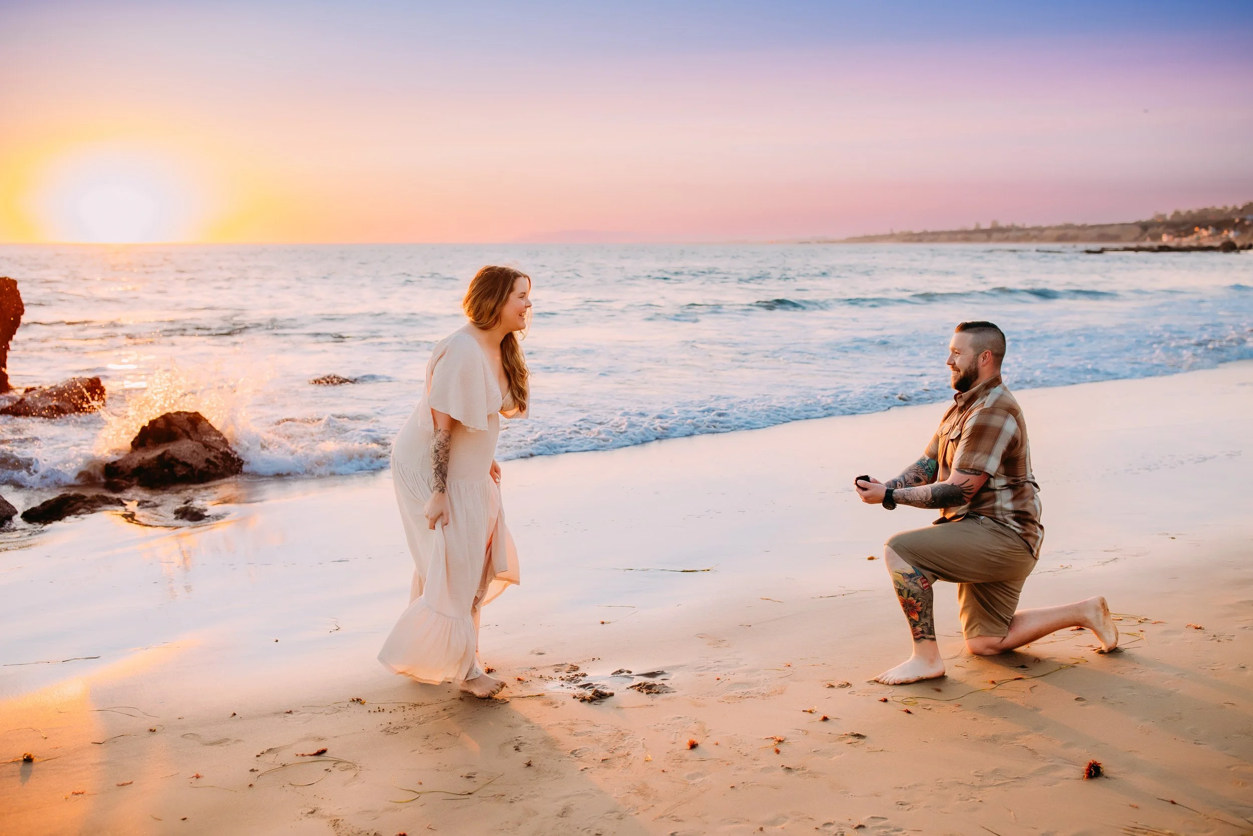 man doing a surprise proposal to his girlfriend during their photo shoot at sunset in Newport Beach, CA