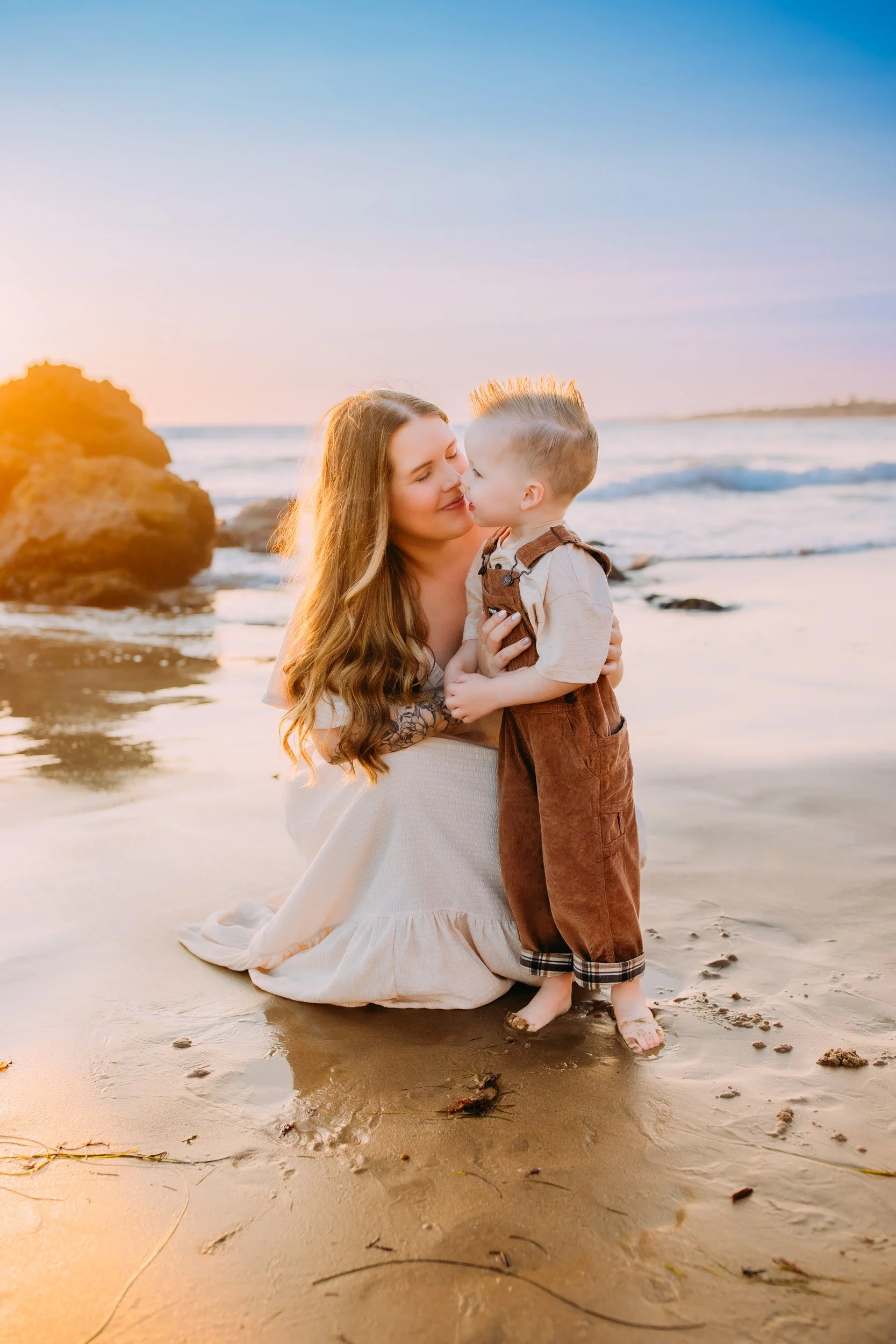mom and son having a sweet affectionate moment together during their sunset beach shoot in Newport Beach, CA