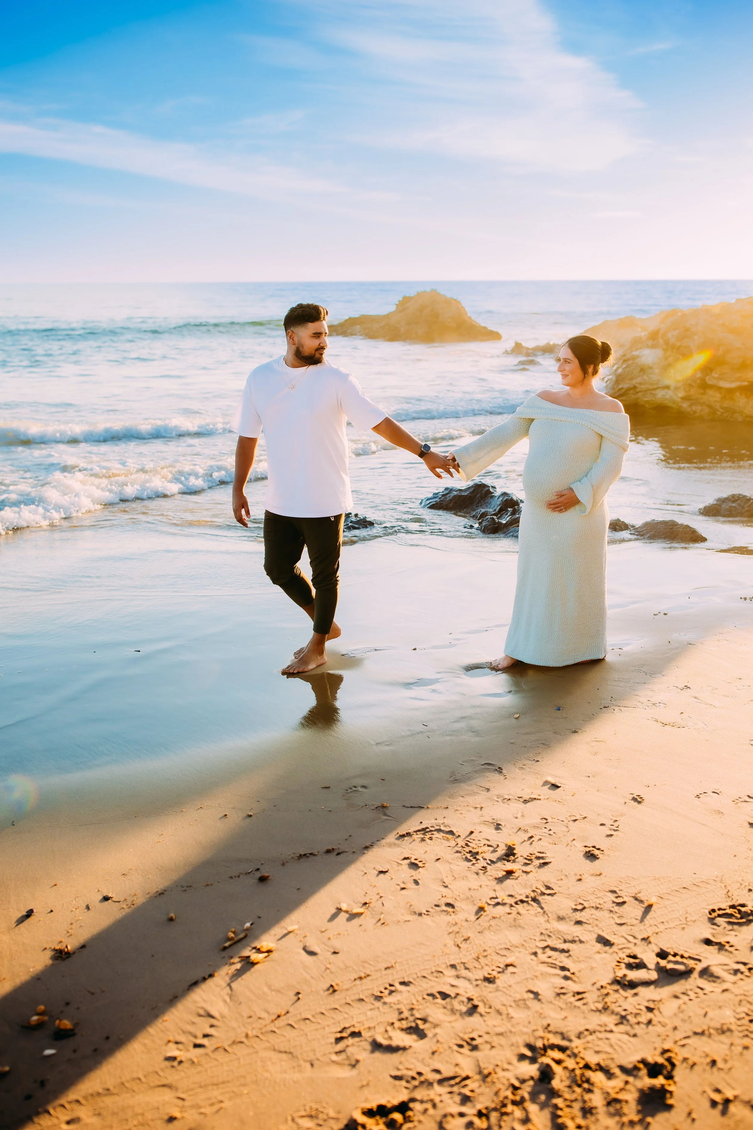 Maternity photos in Newport Beach at sunset with glowing mom and couple on beach