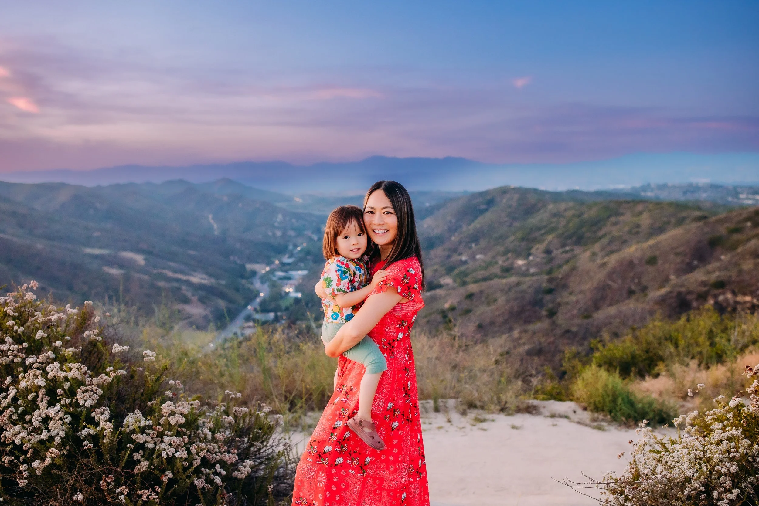 mother and son smiling at the camera with the foothills of Laguna Beach, California in their background
