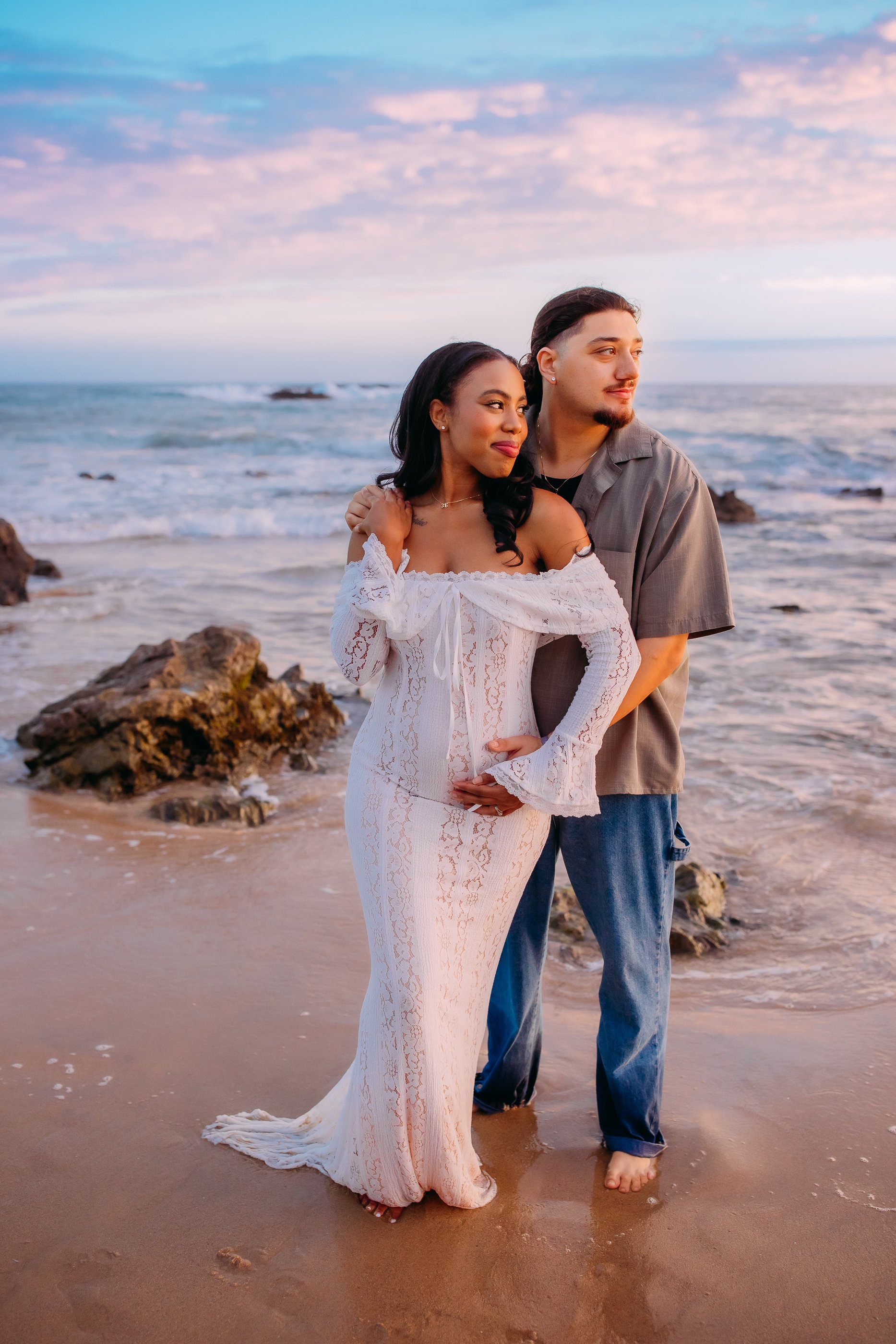 man and women gazing into the sunset during their pregnancy announcement photo session in Newport Beach, California