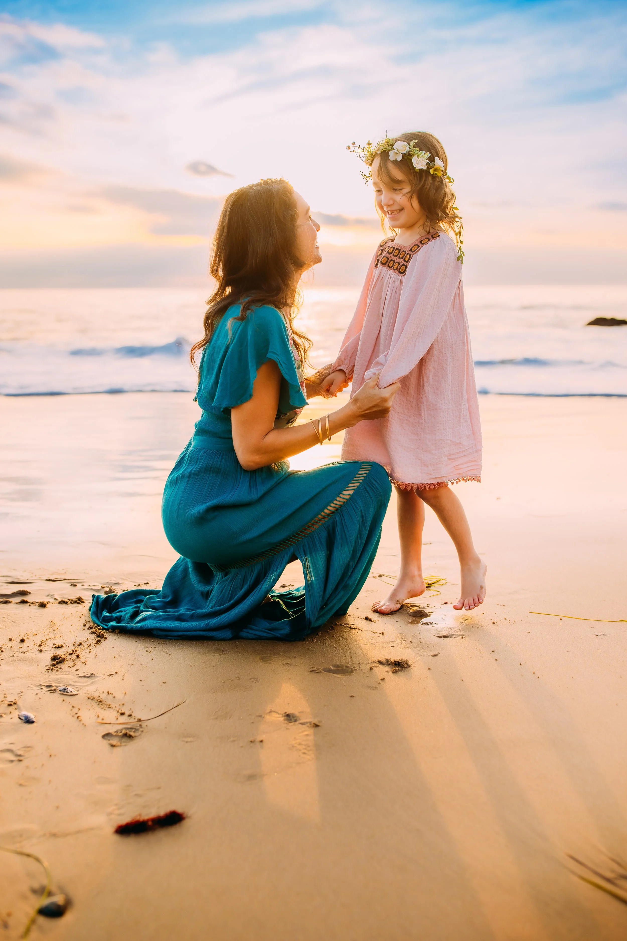 mom squatting down to daughter as they both laugh during their photo session in Newport Beach, California