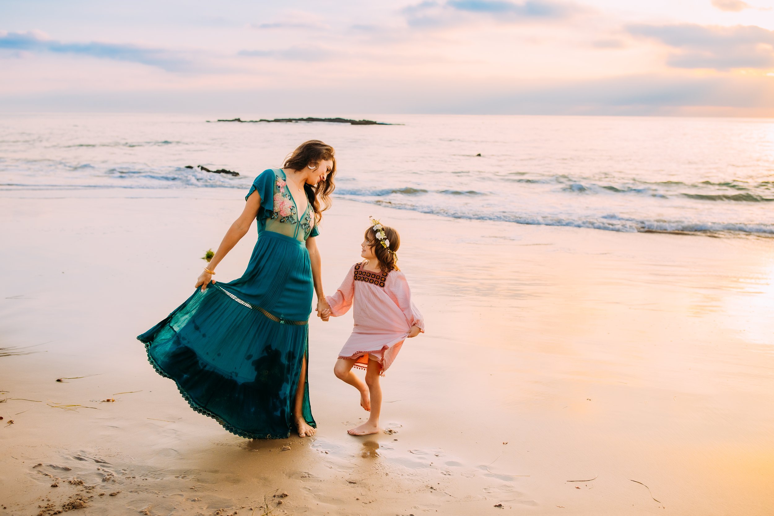 mom and daughter dancing at the beach together during their family photoshoot in Newport Beach, California