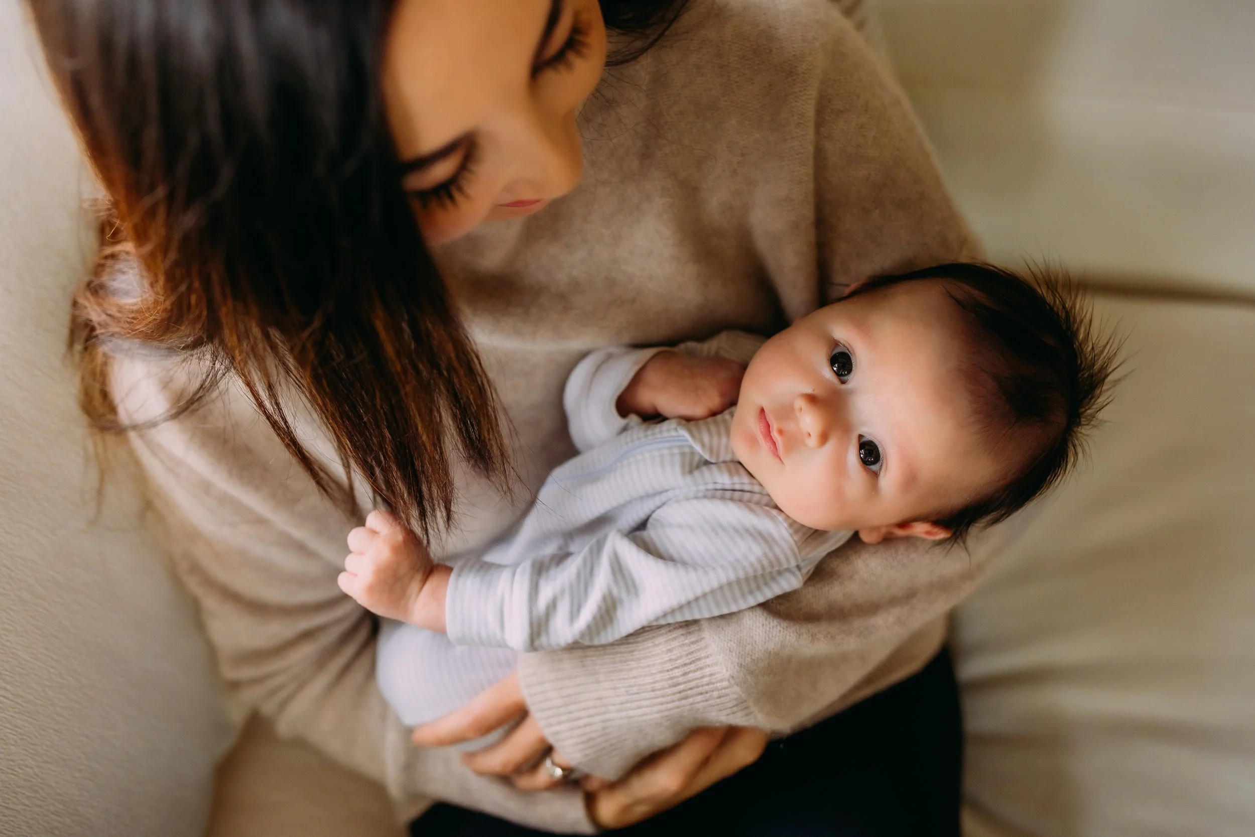 newborn boy looking at the camera while being held in his mom's arms during their in home mini session