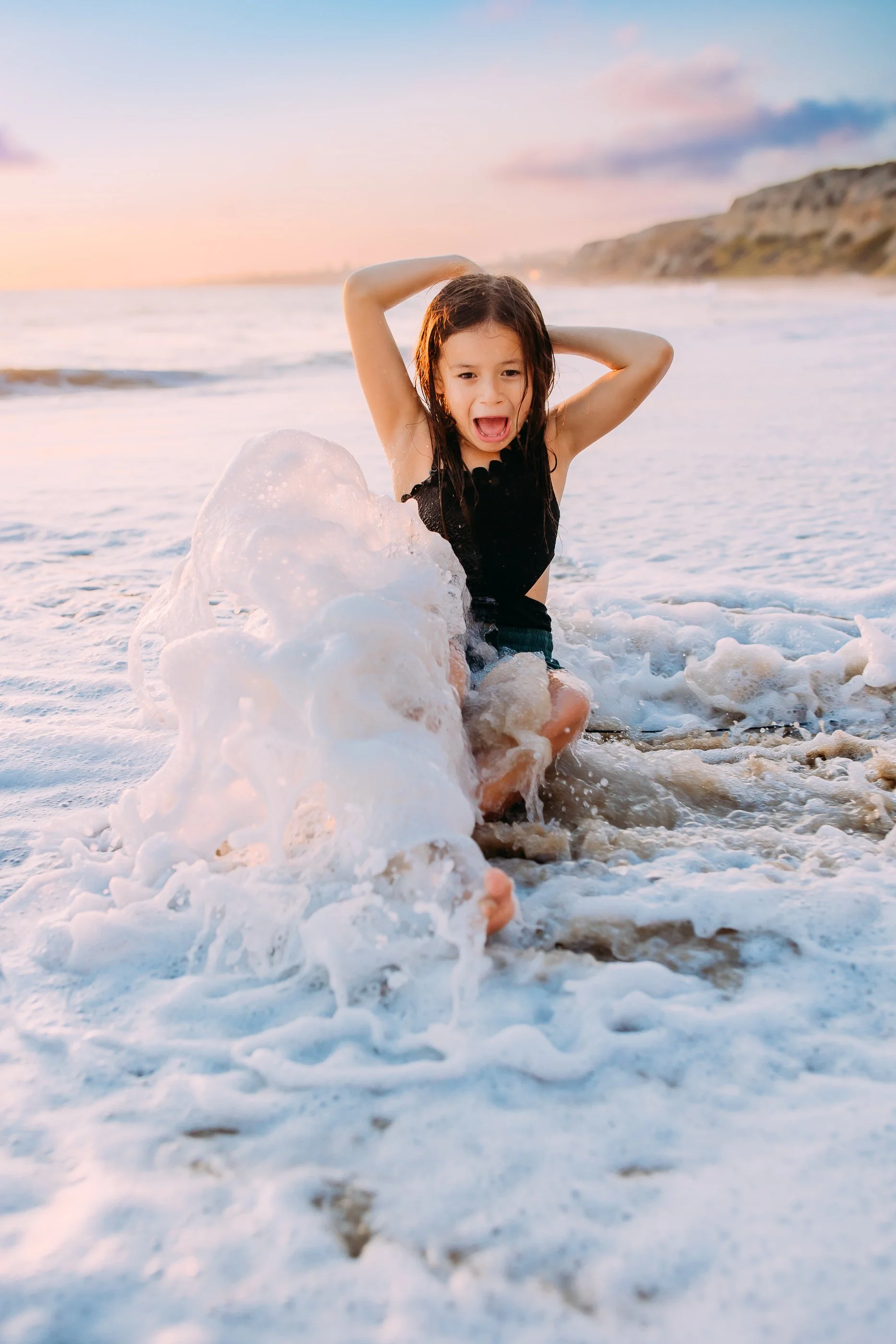 girl playing in the water during her family photo session in Newport Beach, California