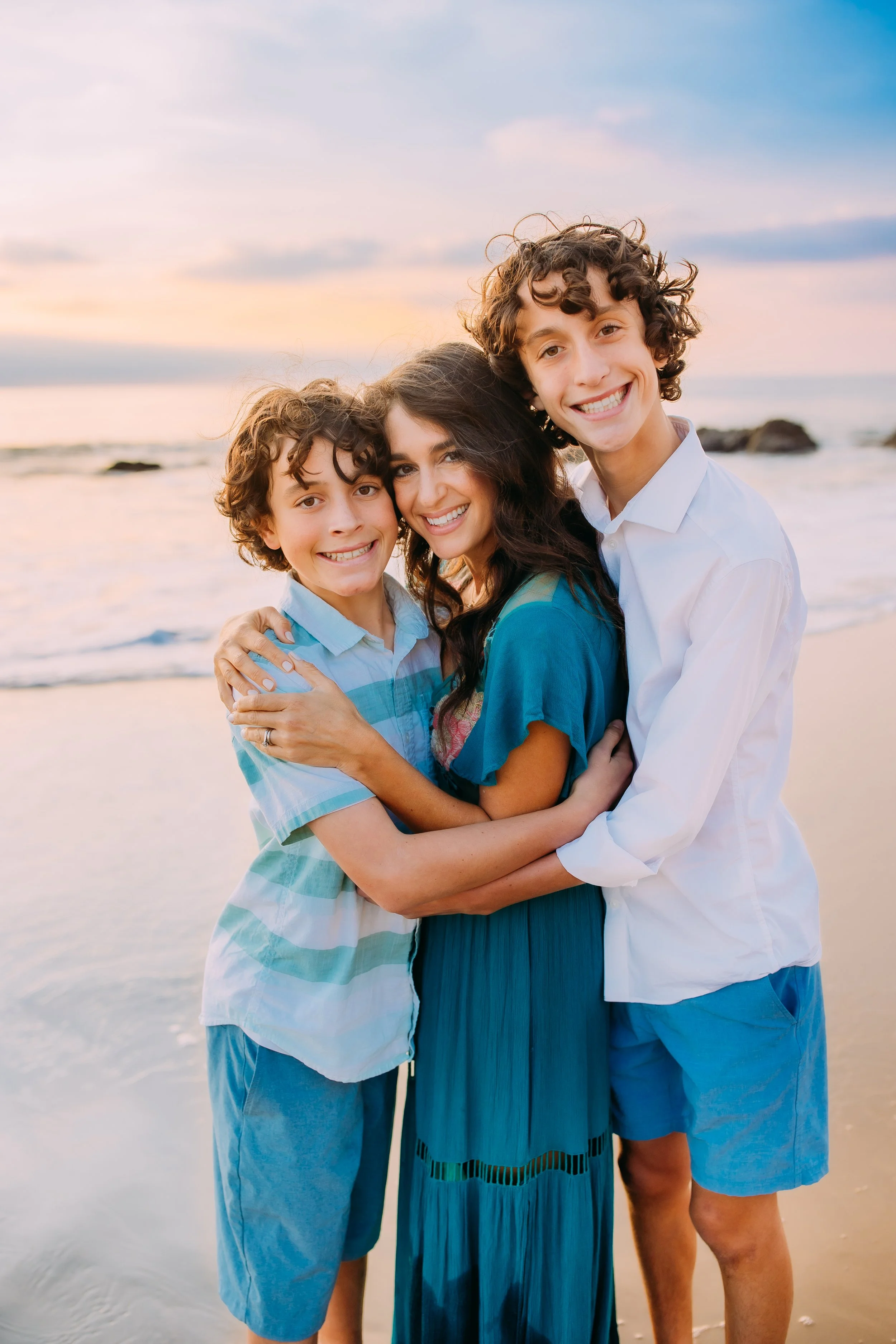 mom and her boys embracing and smiling at the camera in Newport Beach, California