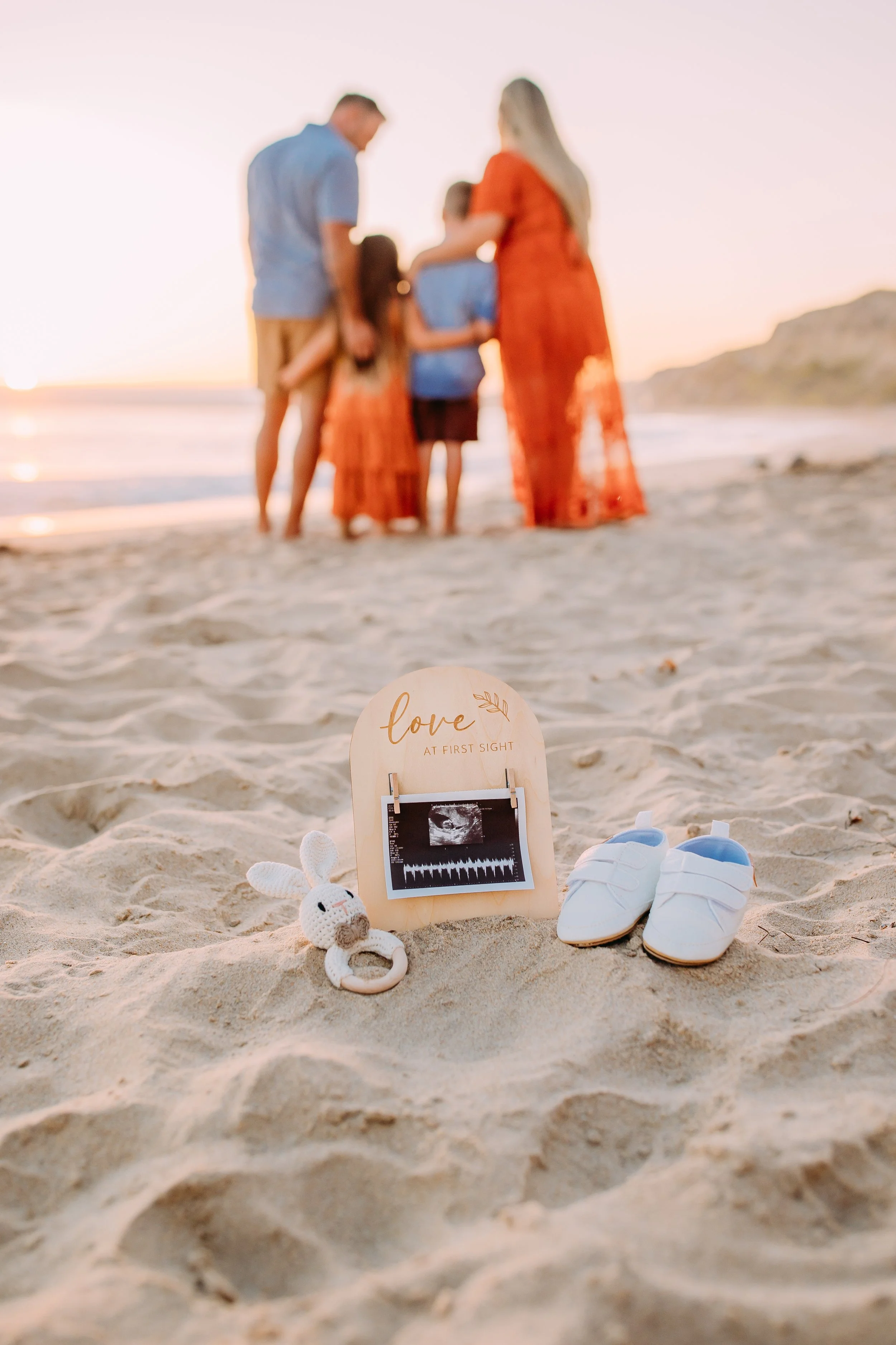 family doing a new baby announcement at the beach during their sunset photo session in Newport Beach, California