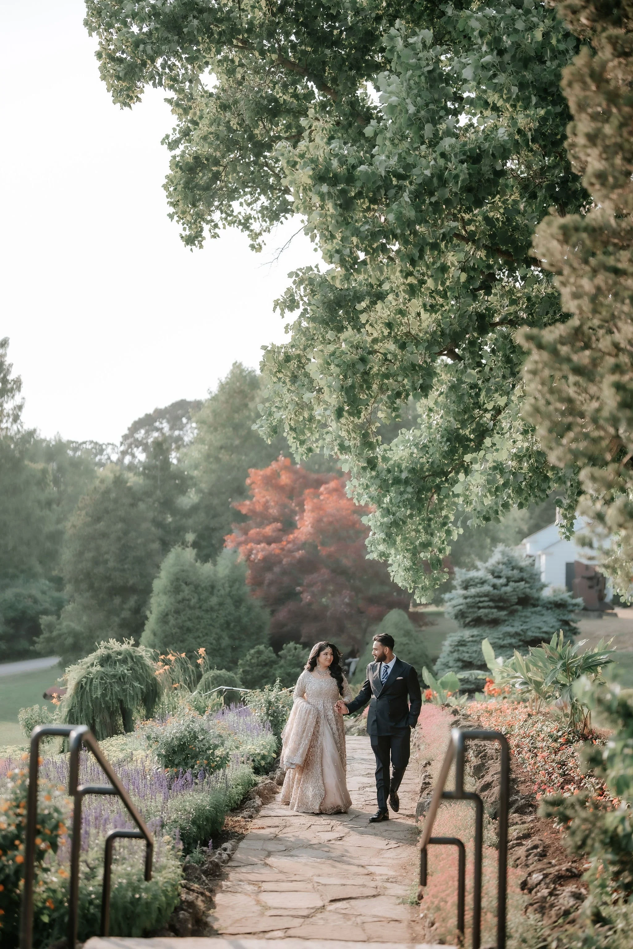 Toronto Muslim wedding photographer – bride and groom walking through garden landscape in evening light.