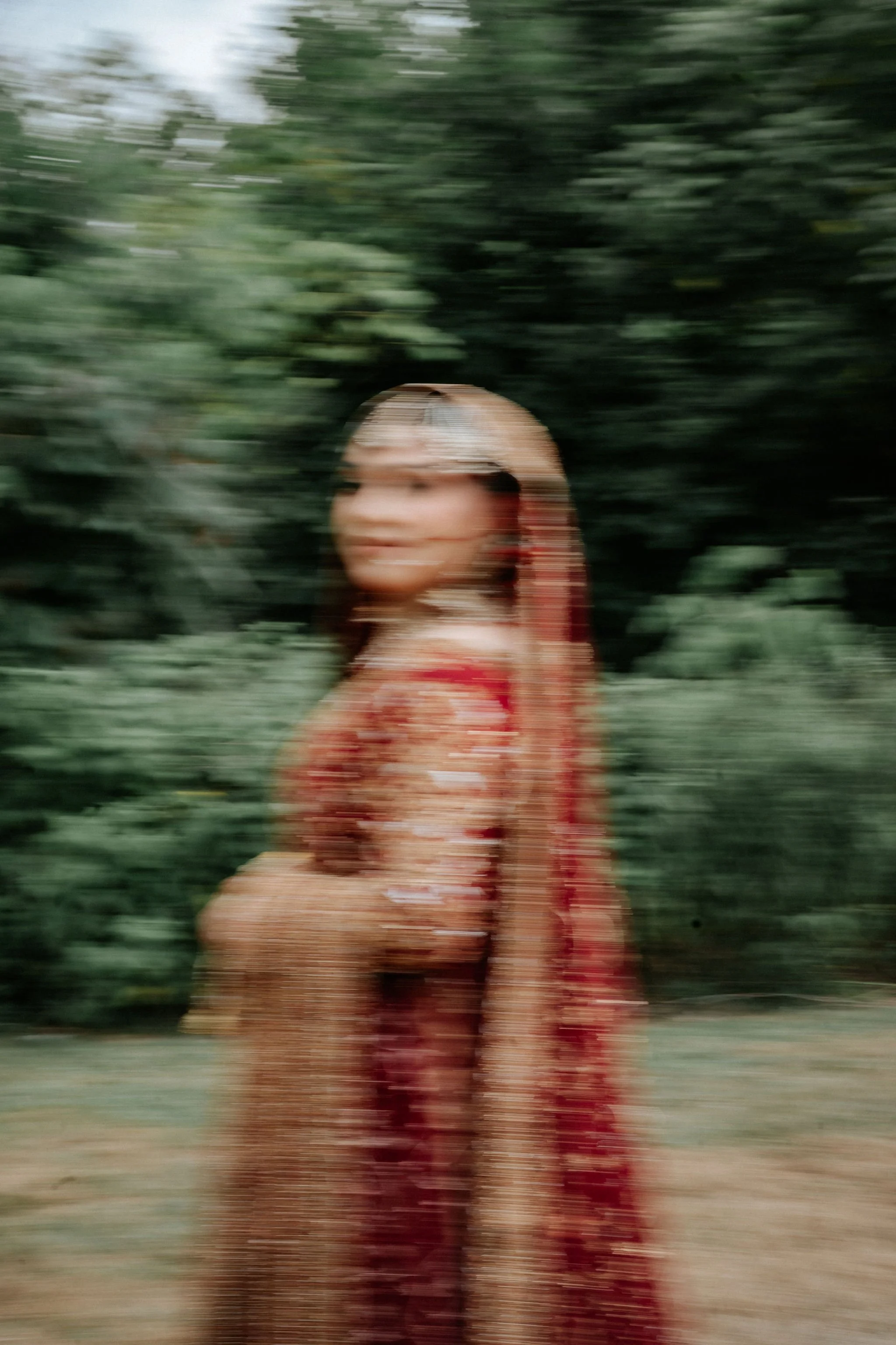 Artistic motion blur portrait of Muslim bride in traditional red lehenga – cinematic Toronto wedding photography.