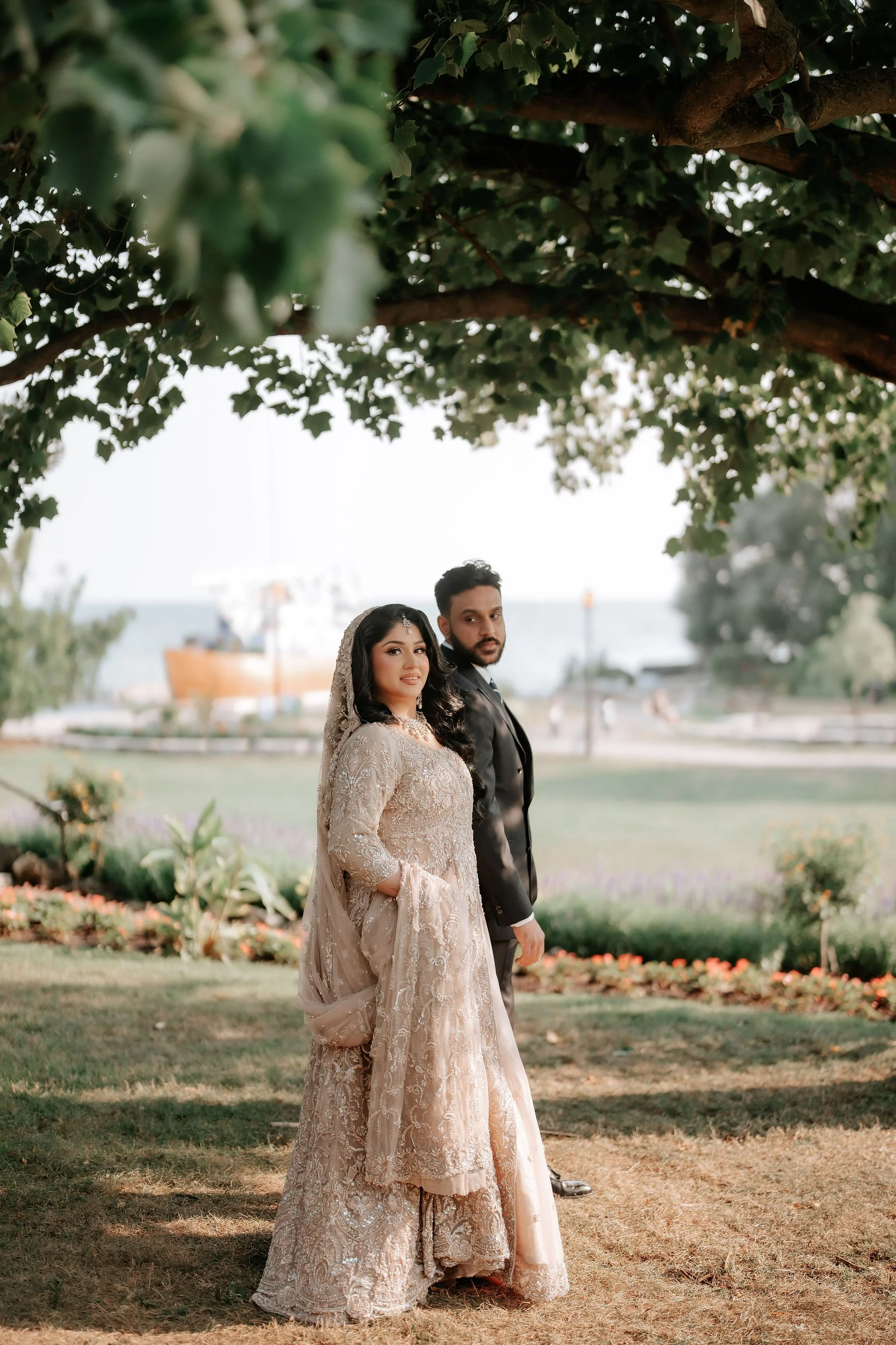 Toronto Muslim wedding portraits – bride and groom standing under tree in elegant traditional attire.
