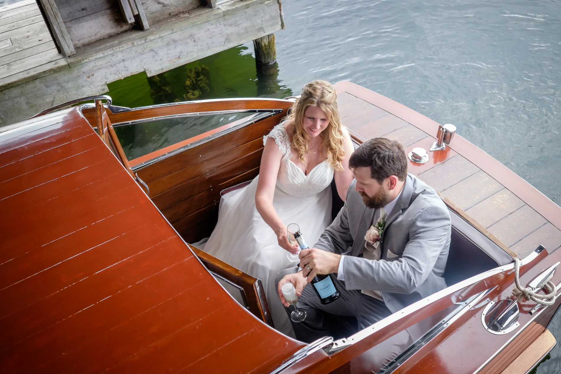 Bride and groom champagne toast, wooden boat.