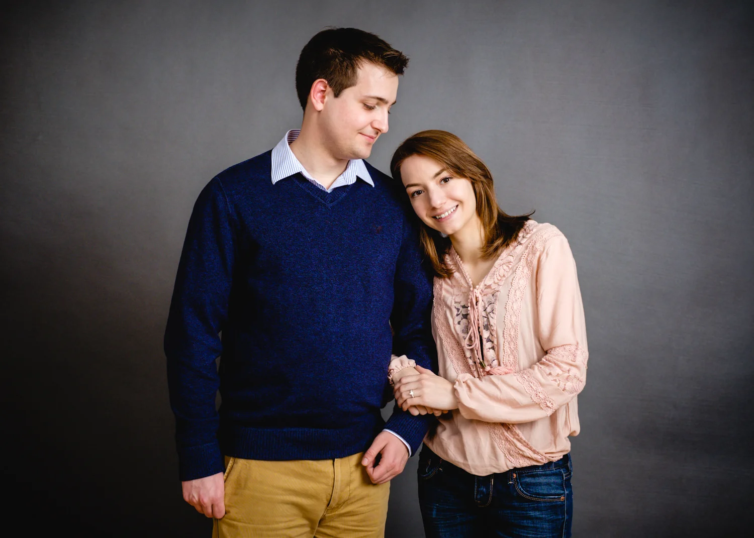 Engagement portraits in studio with a grey backdrop.