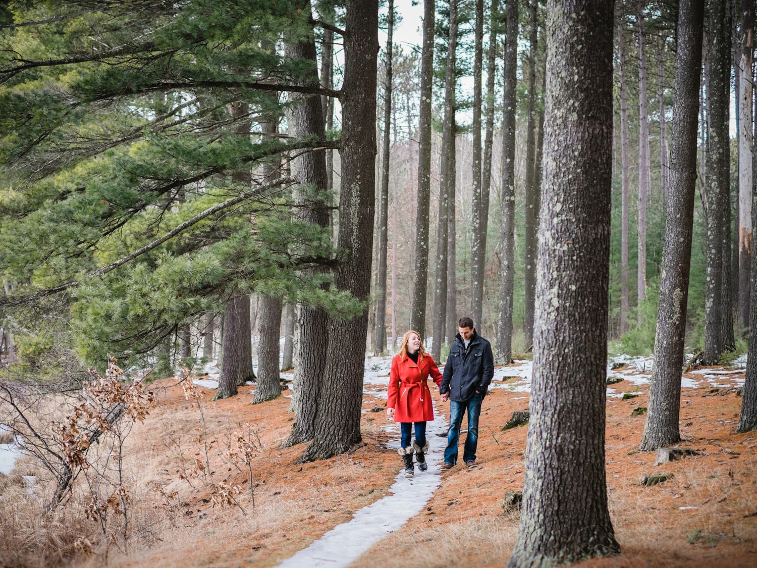 Engaged couple walking in the woods.