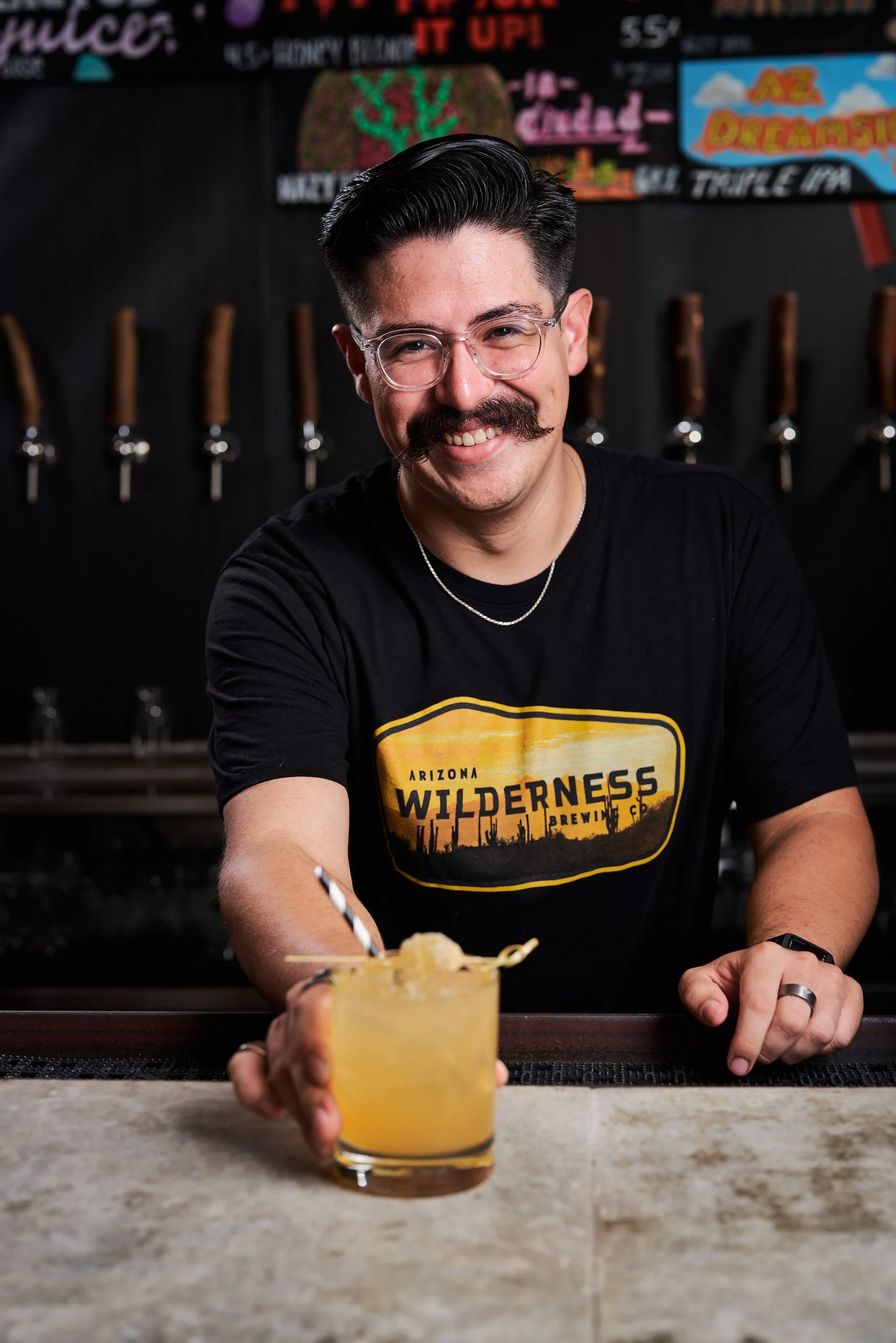 A bartender at Arizona Wilderness Brewery serving a craft cocktail.
