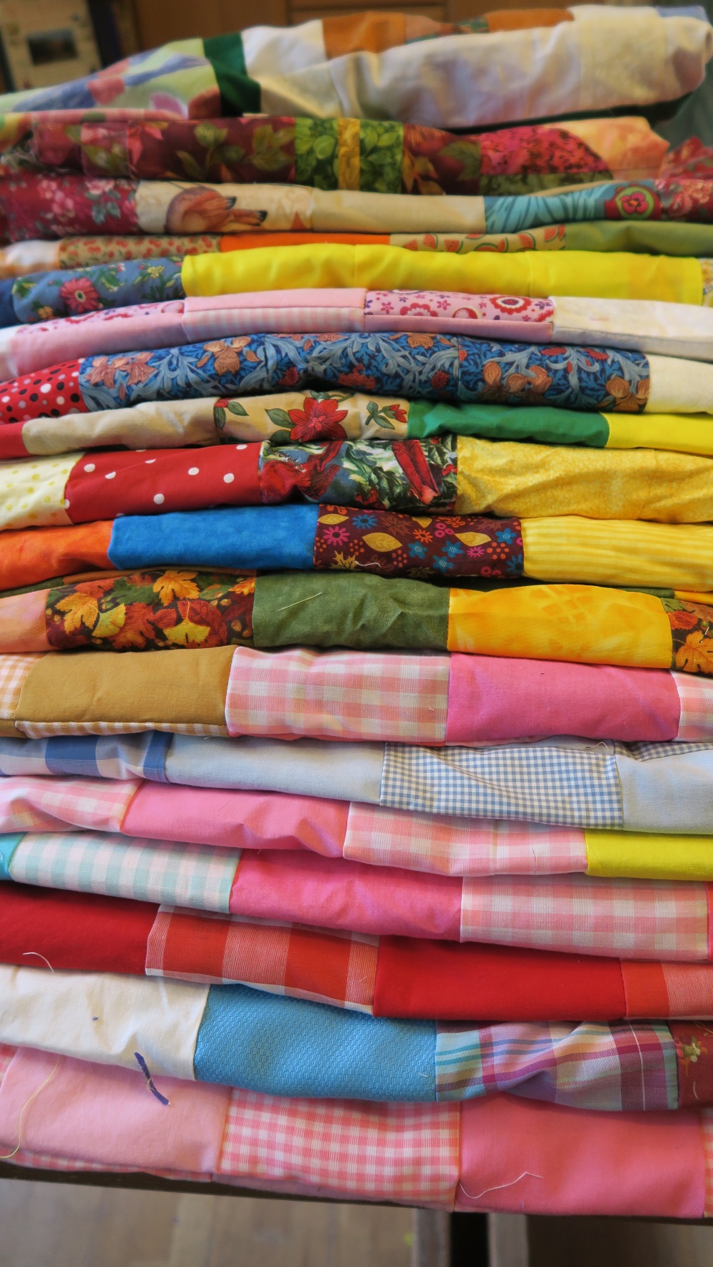 This is my pile of double/queen tops that I have ready to finish. All but the top two were donated by my friend in AZ. She told me that she was using up her mom's gingham - that's why so many with gingham - and she apologized. But it's fine - it really is. When I give them away, I let people choose what they like - so if they don't care for gingham, they will just wait for someone who does like it. At the rate of 10 per month, these will take me through July.