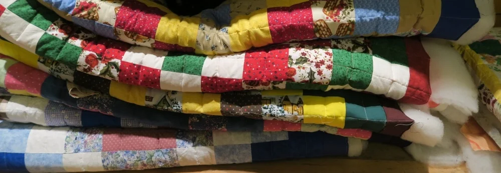 I've learned to work in groups. This is a pile of 6 quilted quilts plus there is one to the right of these - barely showing in this picture. Once I get them bound and washed, I don't let the cats sit on them anymore. These are "May's" quilts - but only 7. I am now out of batting and need to get to the store to get another bolt. Don't worry. I can get this batting locally - about 1/2 mile from my house and 50 meters of poly batting costs me less than most of you spend if you take your family w/kids out to eat once in a sit down restaurant in the USA.