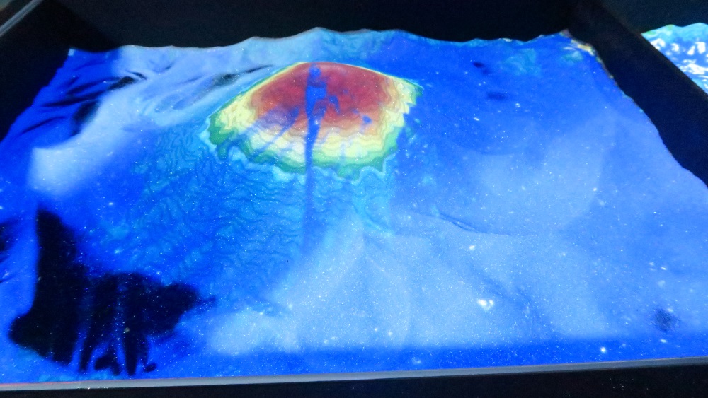 The object here is to build a relief map. under a black light. It is white sand. Kids love sticking their hands in the sand - such simple stress relief!