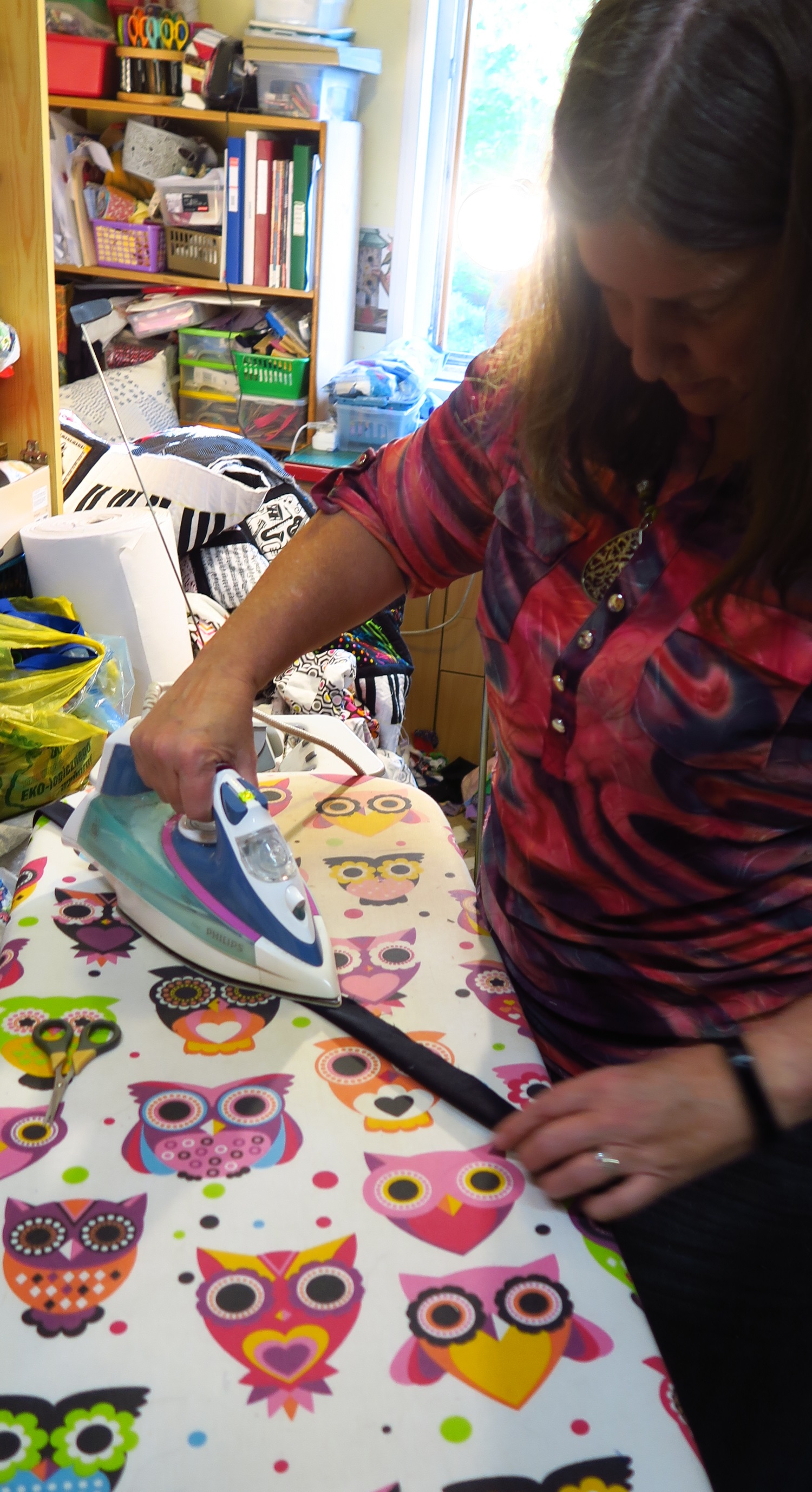 She's pressing the binding strips in half. She needed 5 strips of our black fabric. It's about 62" wide, so we're okay with 5 strips.
