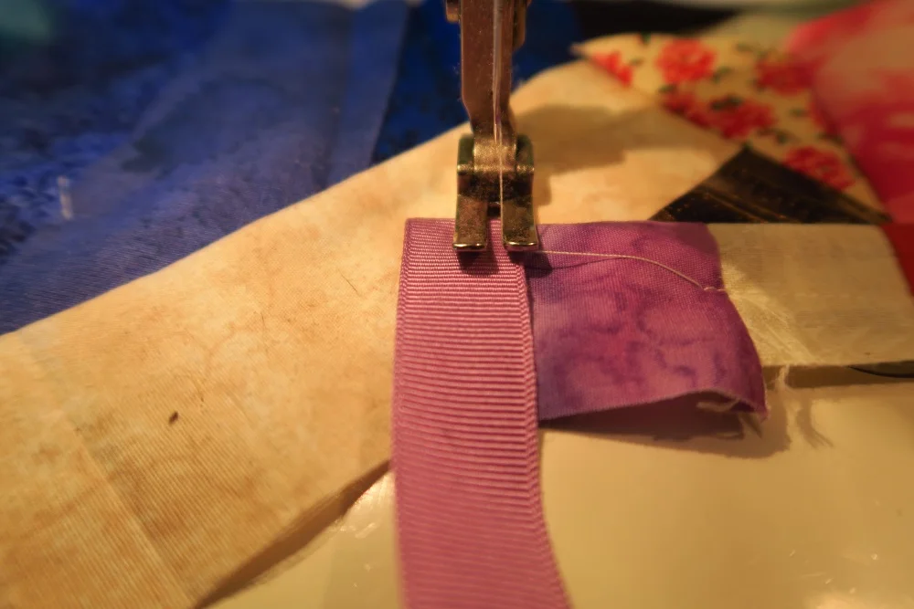 The previous bit left a bit of a raw edge that will show into the seam, so I covered it with ribbon which I folded under. This way there will be no raw edges in the finished strip of fabric.