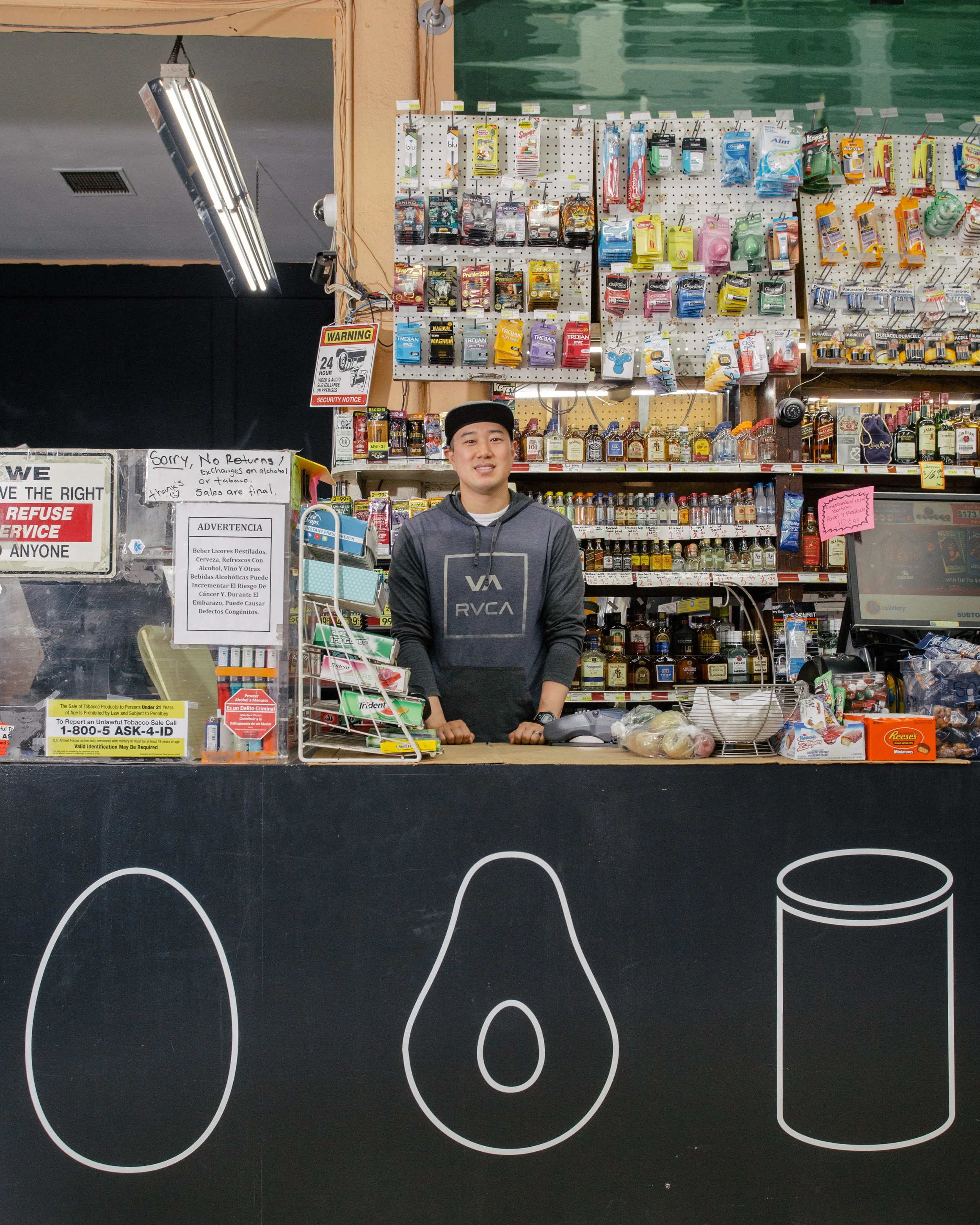 Andy Lee, owner of Sam’s Corner Store, standing behind his new check-out counter, featuring healthy food icons. (This project was a part of the Healthy Neighborhood Market Network, in collaboration with the LA Food Policy Council.)