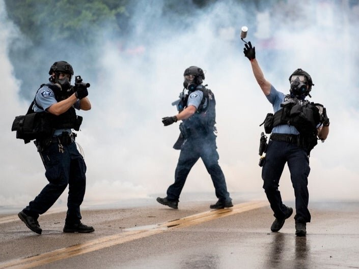  Police officers throw tear gas canisters to disperse crowds. 