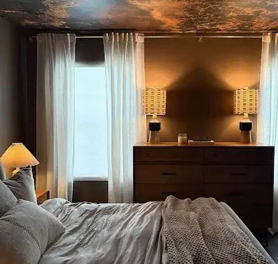 This one just feels like home 🤍 We leaned into all the little details here&mdash;the soft glow from the layered lighting, warm wood tones to ground the space, and those sheer drapes that keep it feeling light but still cozy. The ceiling ended up bei