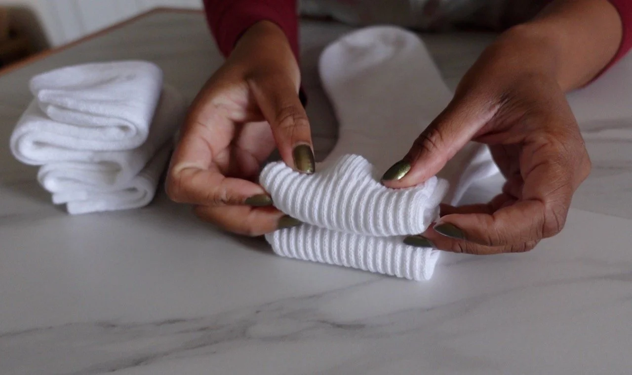 hands folding white socks into stripe pattern