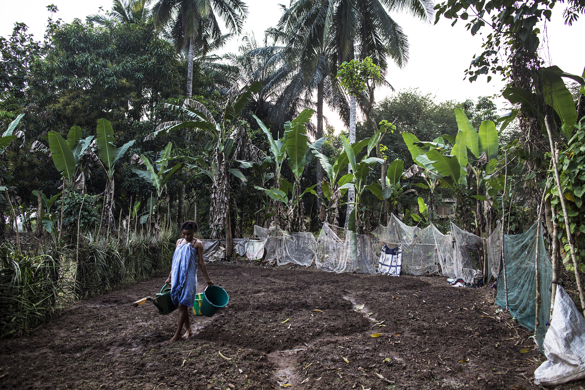 Mariatu Bangura, 18, of Rokupr, waters her garden near her house. She recently started the garden so that she can make more money to provide for her son and herself. 