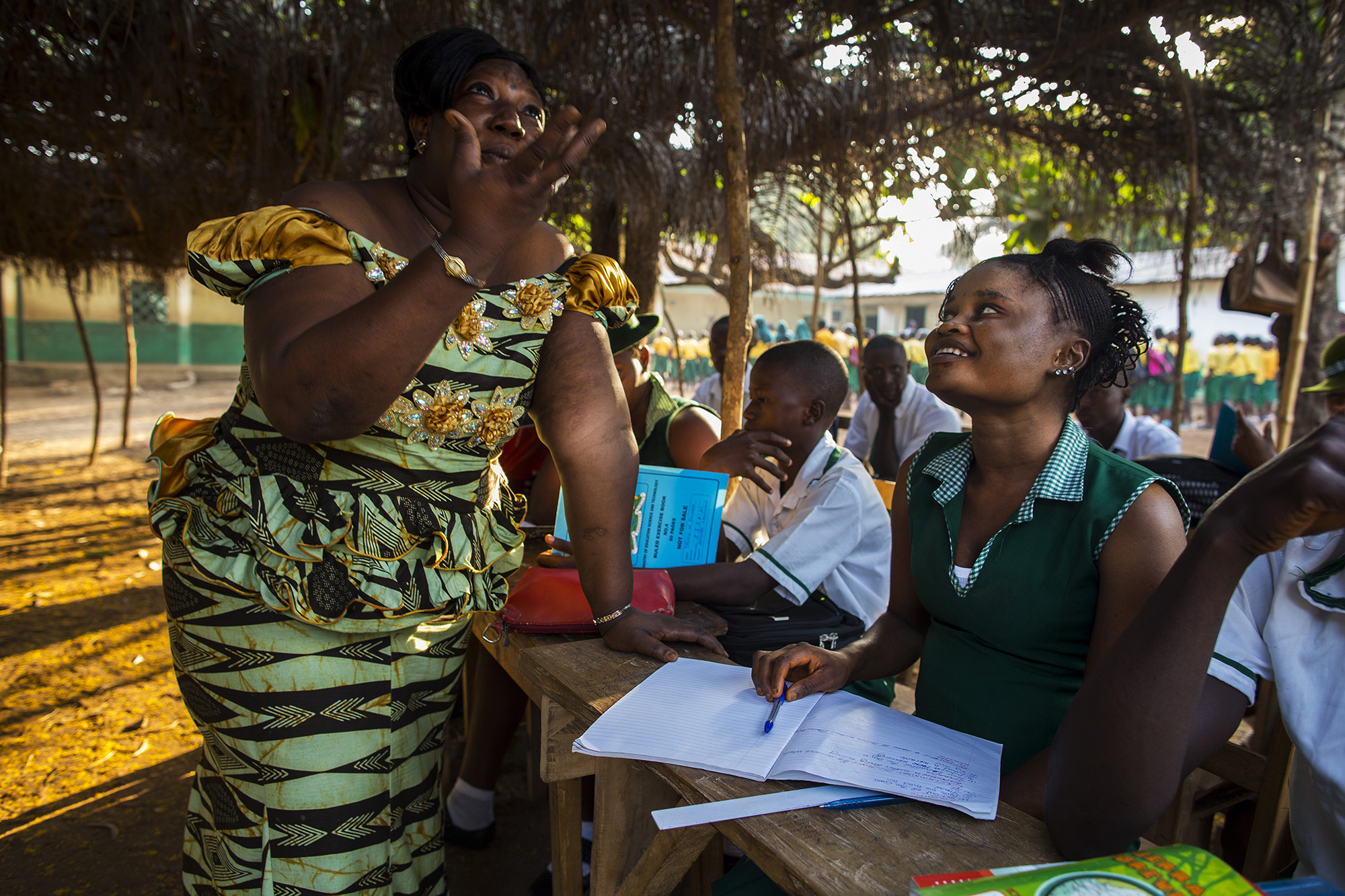 Mabinty Kubra Turay, left, Manager of Kubra Agricultural Secondary School, talks with Mariatu Bangura, 18, of Rokupr, before class begins. Mabinty helped Mariatu return to regular school after she attended the remedial school following the birth of