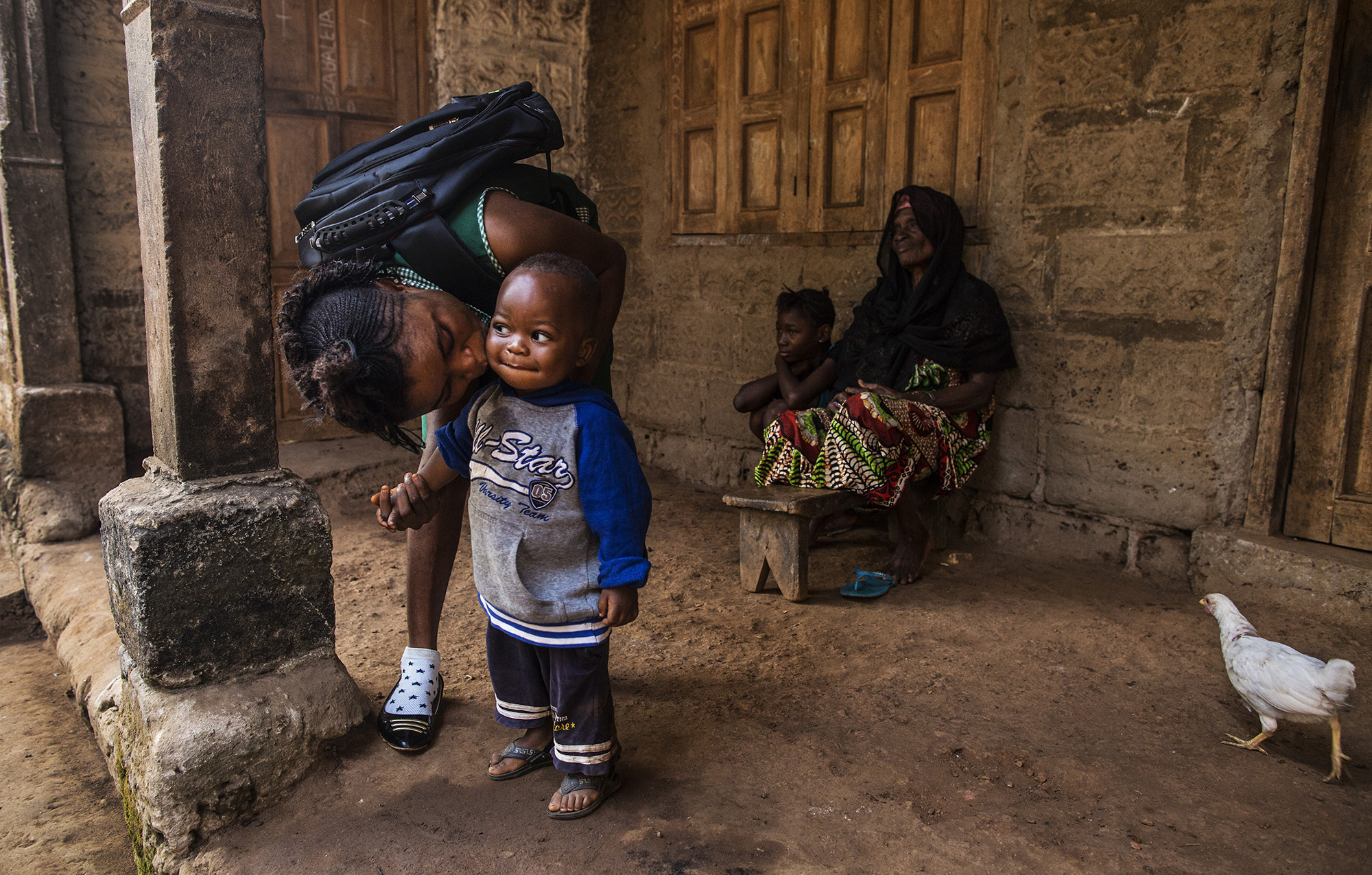 Mariatu Bangura, 18, of Rokupr, left, kisses her son, Abduli, before going to school. Abduli stays with Mariatu's grandmother, Yamaya Kamara, back right, while she attends school. Also pictured on back left is Mariatu's cousin, Ya Alimamy Kamara. &n