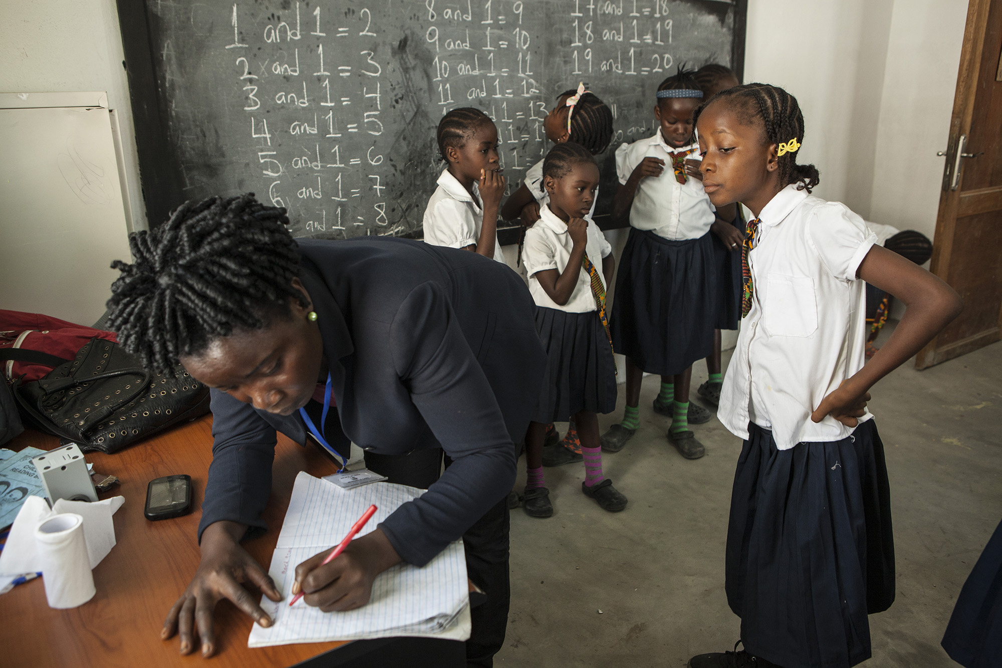 Mercy watches as a teacher corrects her homework while at school. 