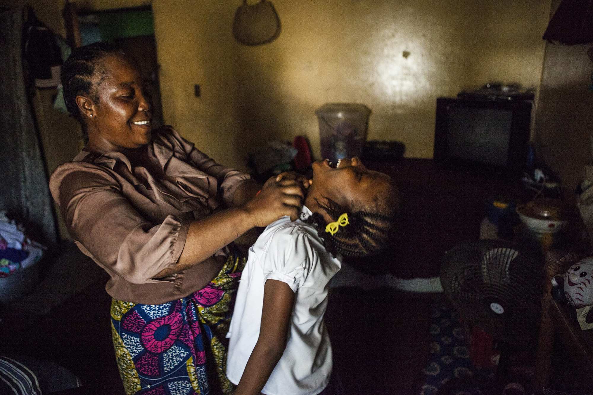 Martu Weefor, Mercy's foster mother, helps her change out of her school uniform after arriving home from school. 