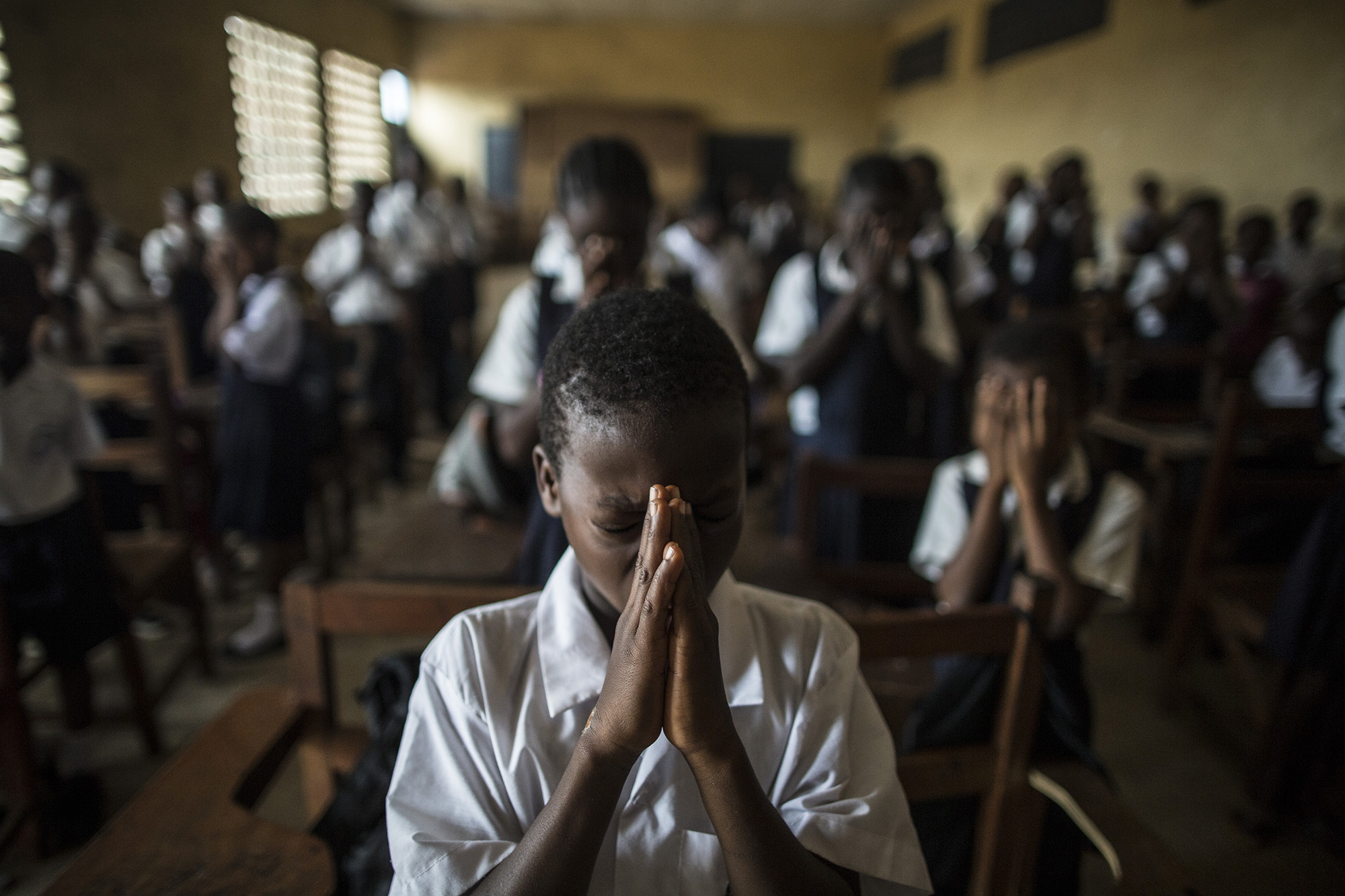  A boy prays on the first day of school following the Ebola epidemic in Monrovia, Liberia.&nbsp; 