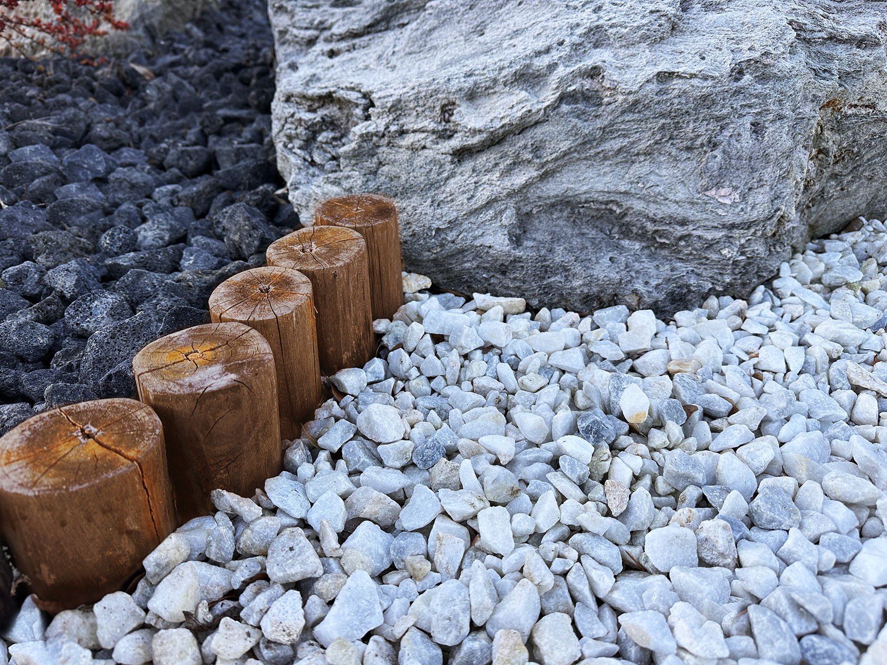  Teak log borders intersect with feather rock boulders with large, sweeping curves. 