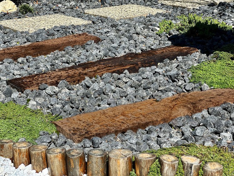  Remaining segments from the railroad tie retaining wall are used to continue the pathway to exposed aggregate walkways surrounding the home. 