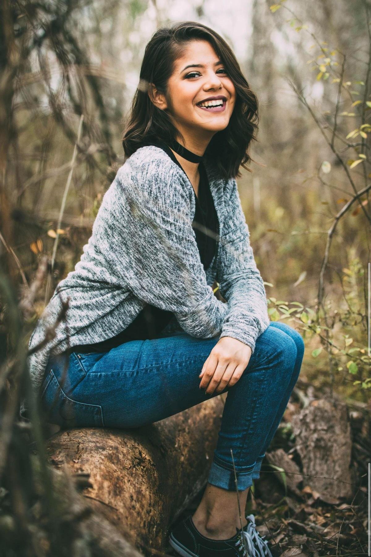 Portrait of a woman sitting on a fallen log, smiling, Orkams collab series