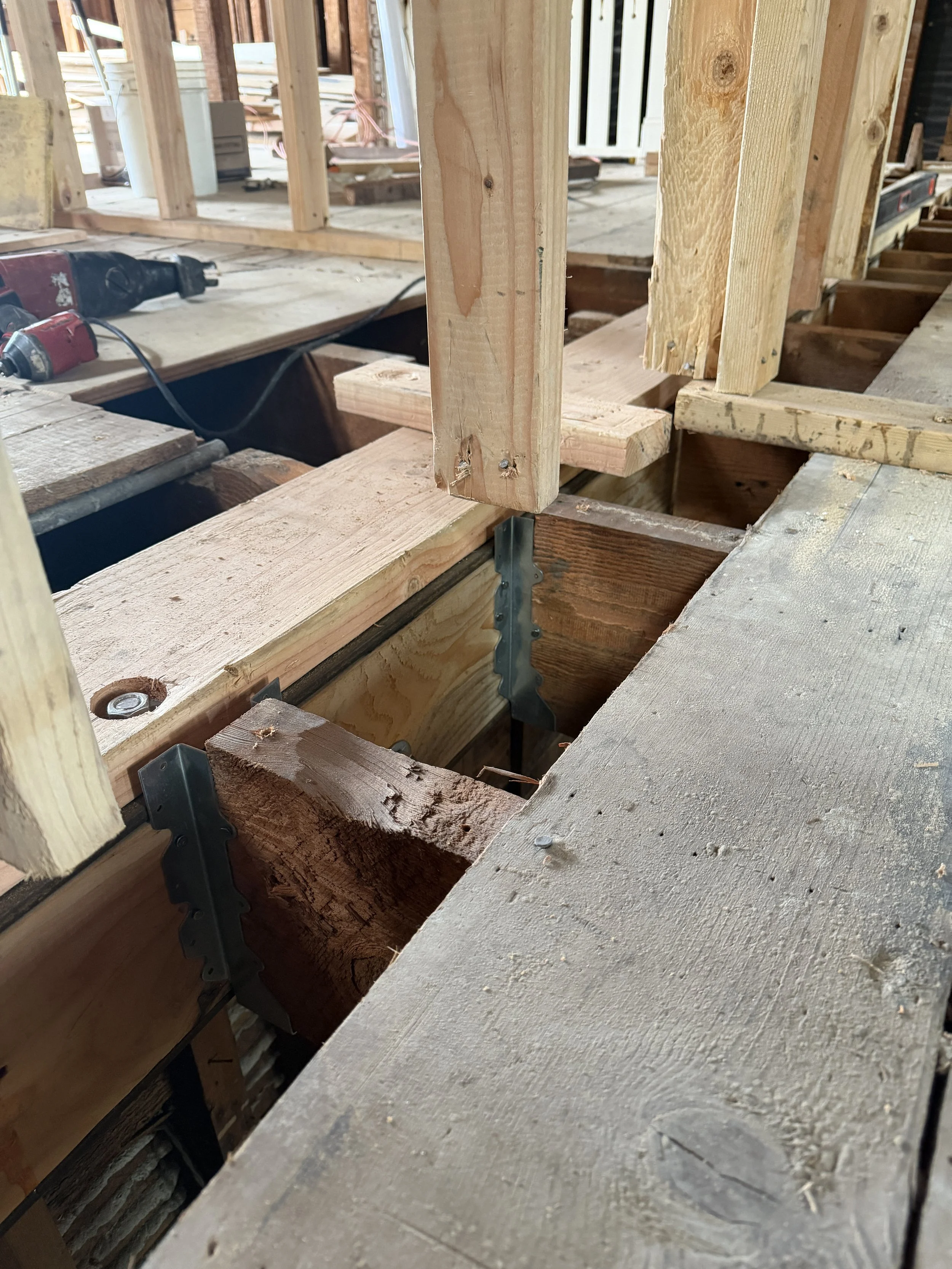 The steel beam, with a wood nailer installed on top, is set flush with the existing wood floor framing. The wood nailer provides a solid surface for fastening the floor sheathing and helps prevent future floor squeaks that could occur if the steel be