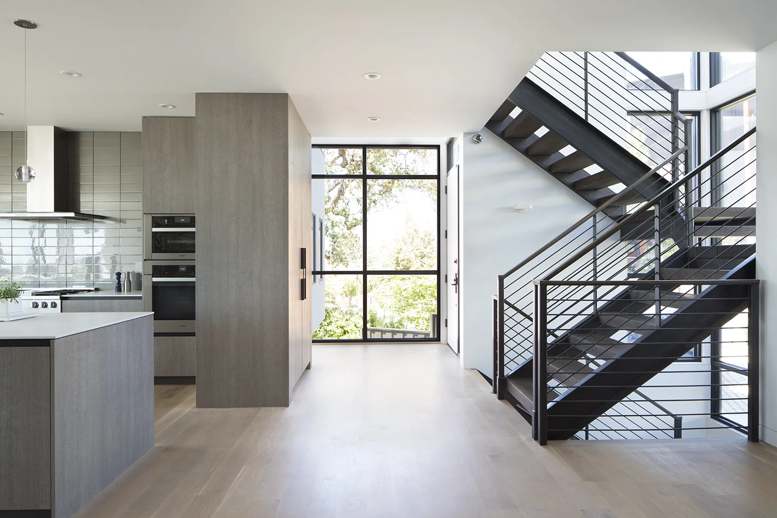 The kitchen is to the left of the stairs.