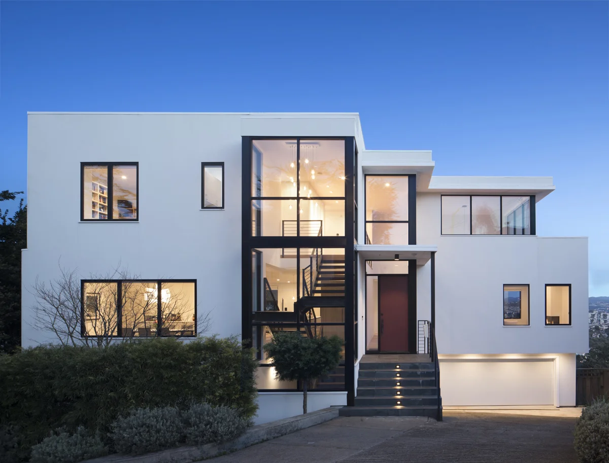 At night, light glows through the large windows of the family home.
