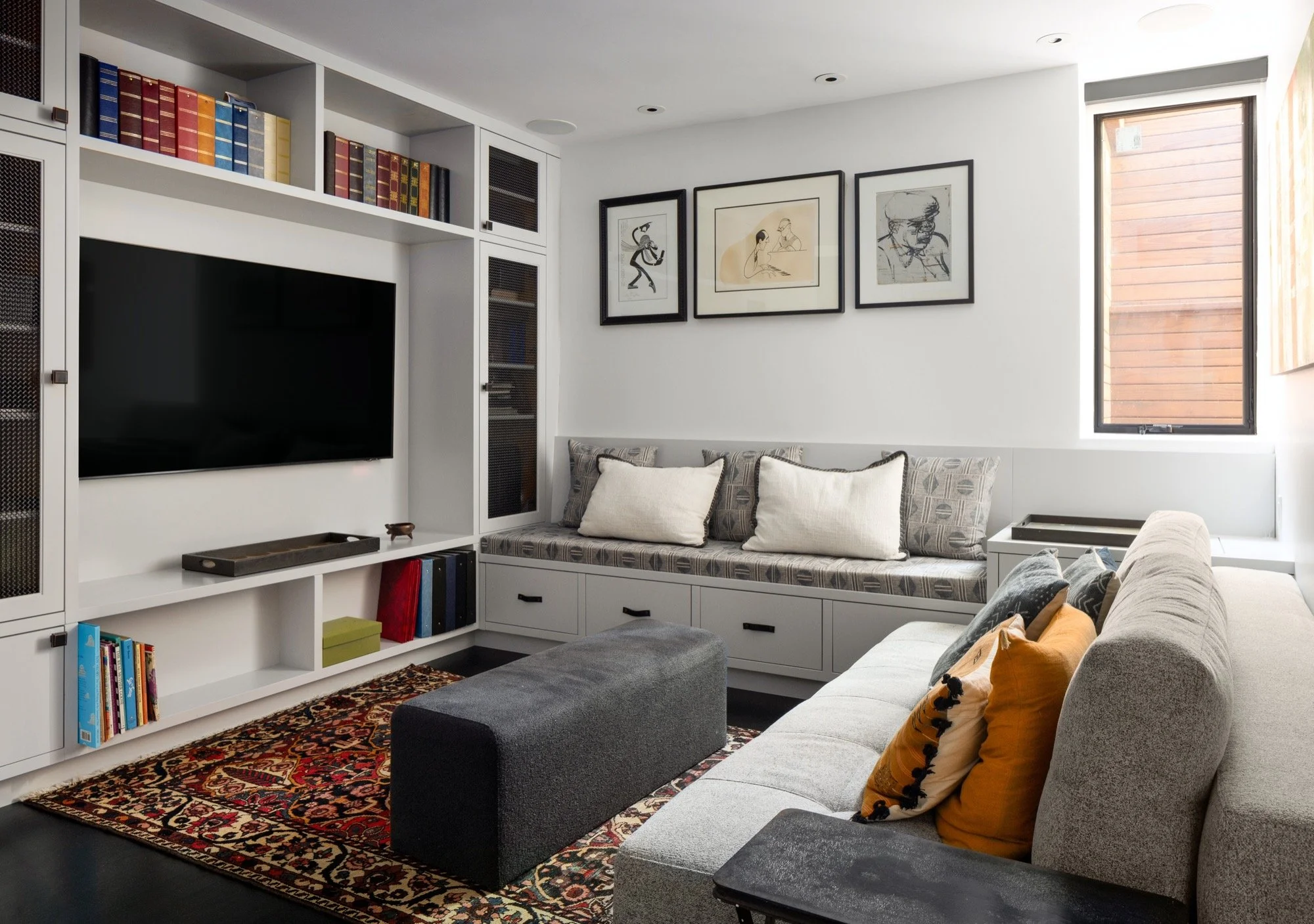  A TV room with a built in media cabinet and couch with storage. 