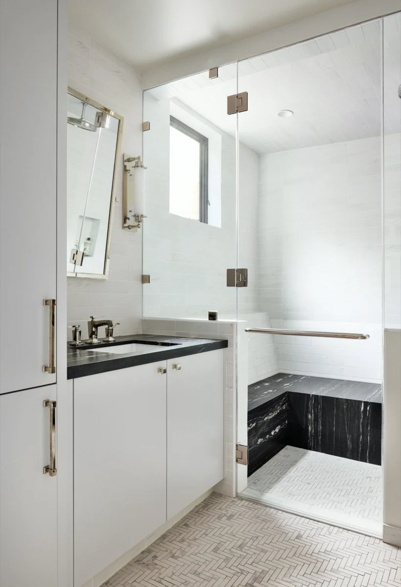  A black and white bathroom with a walk in shower. 