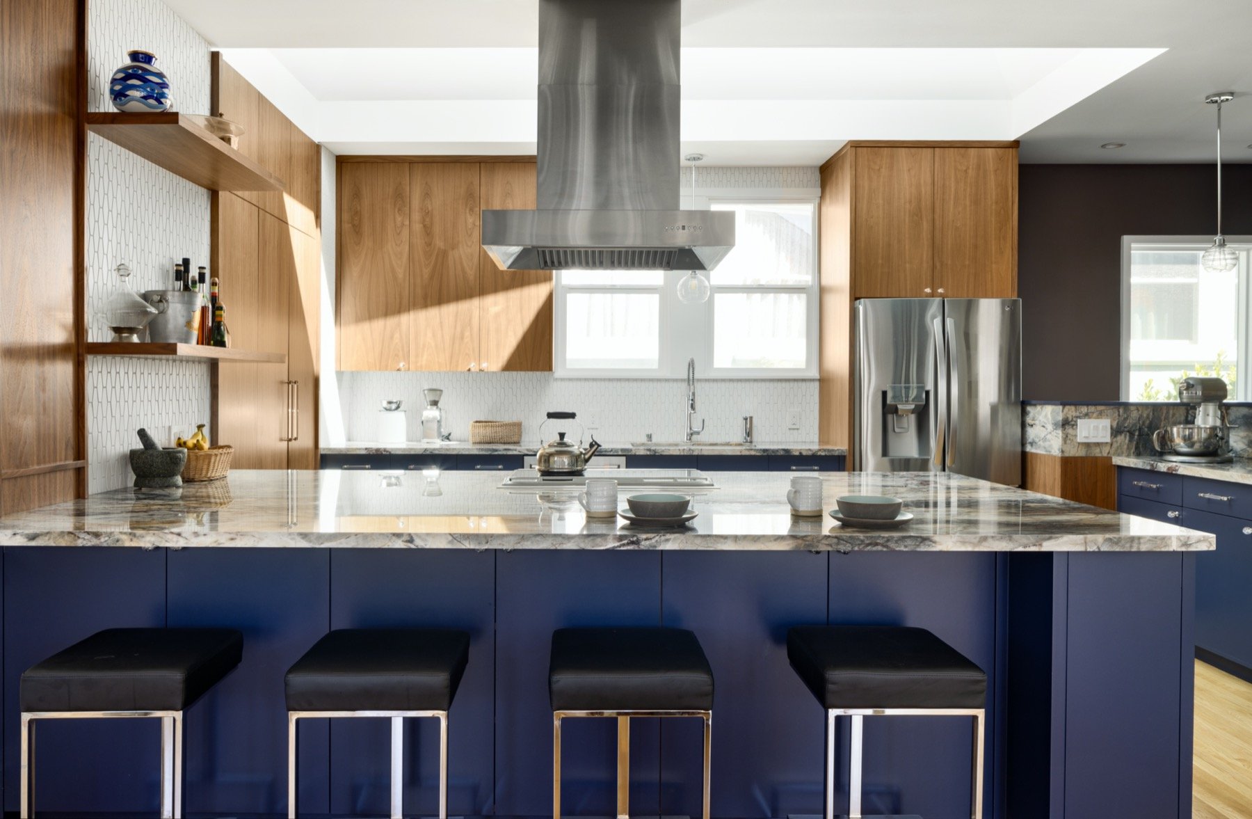  A kitchen with wood cabinets and a navy island, and steel accents. 