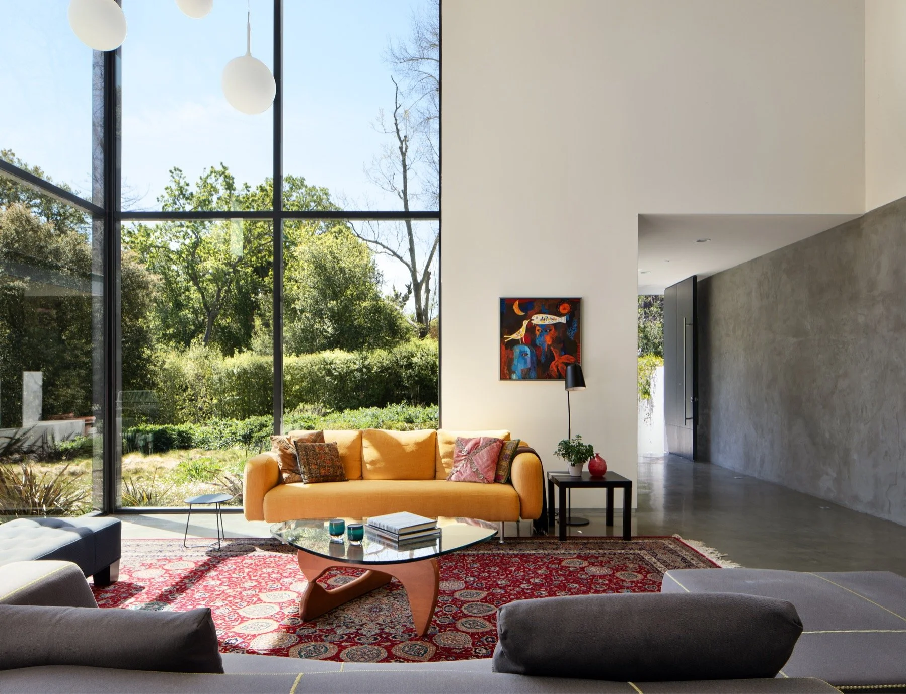  The living room has large steel framed windows and a slate grey wall. 