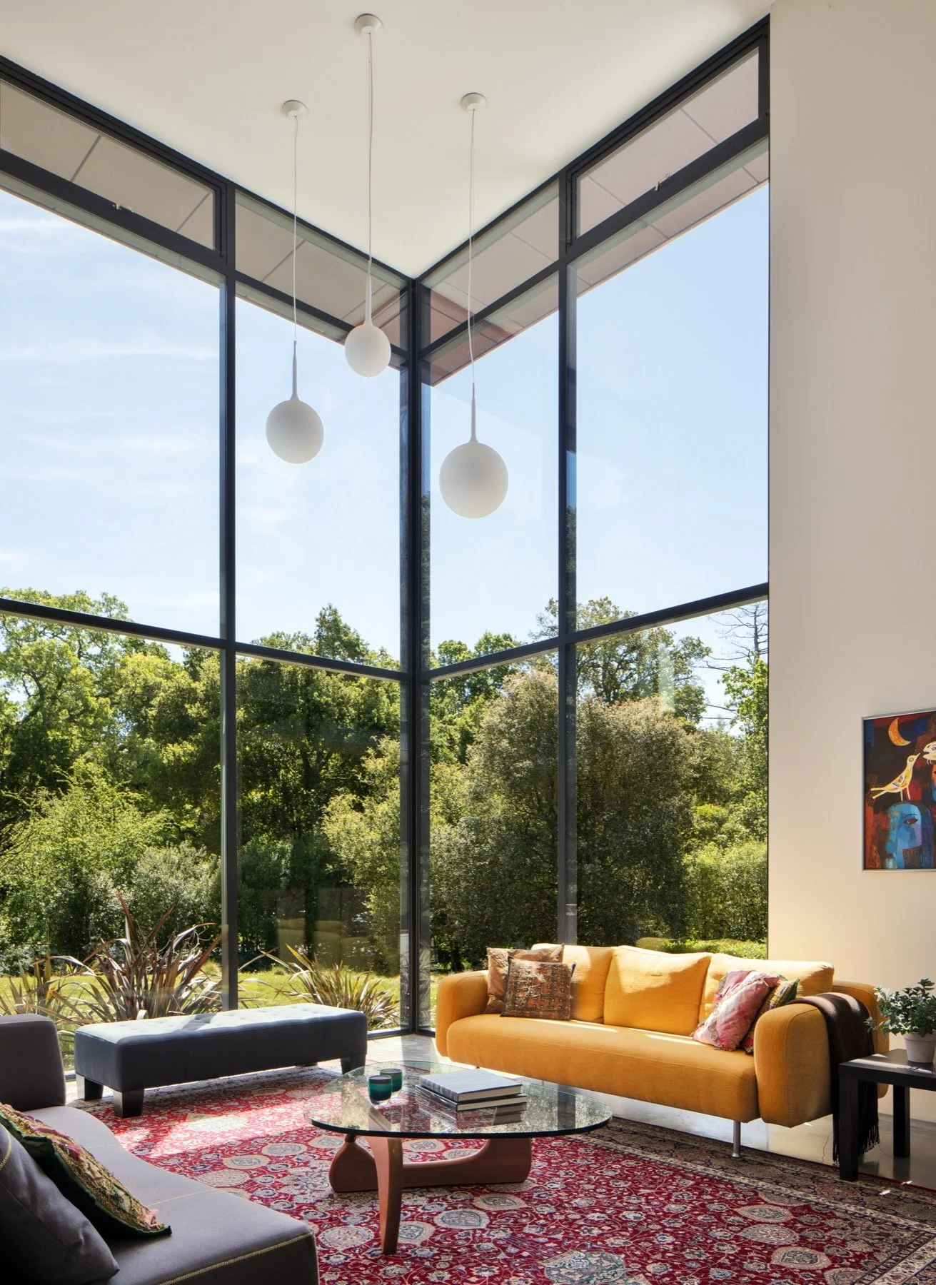 The living room has double height windows and modern furniture grounded by a traditional rug. 