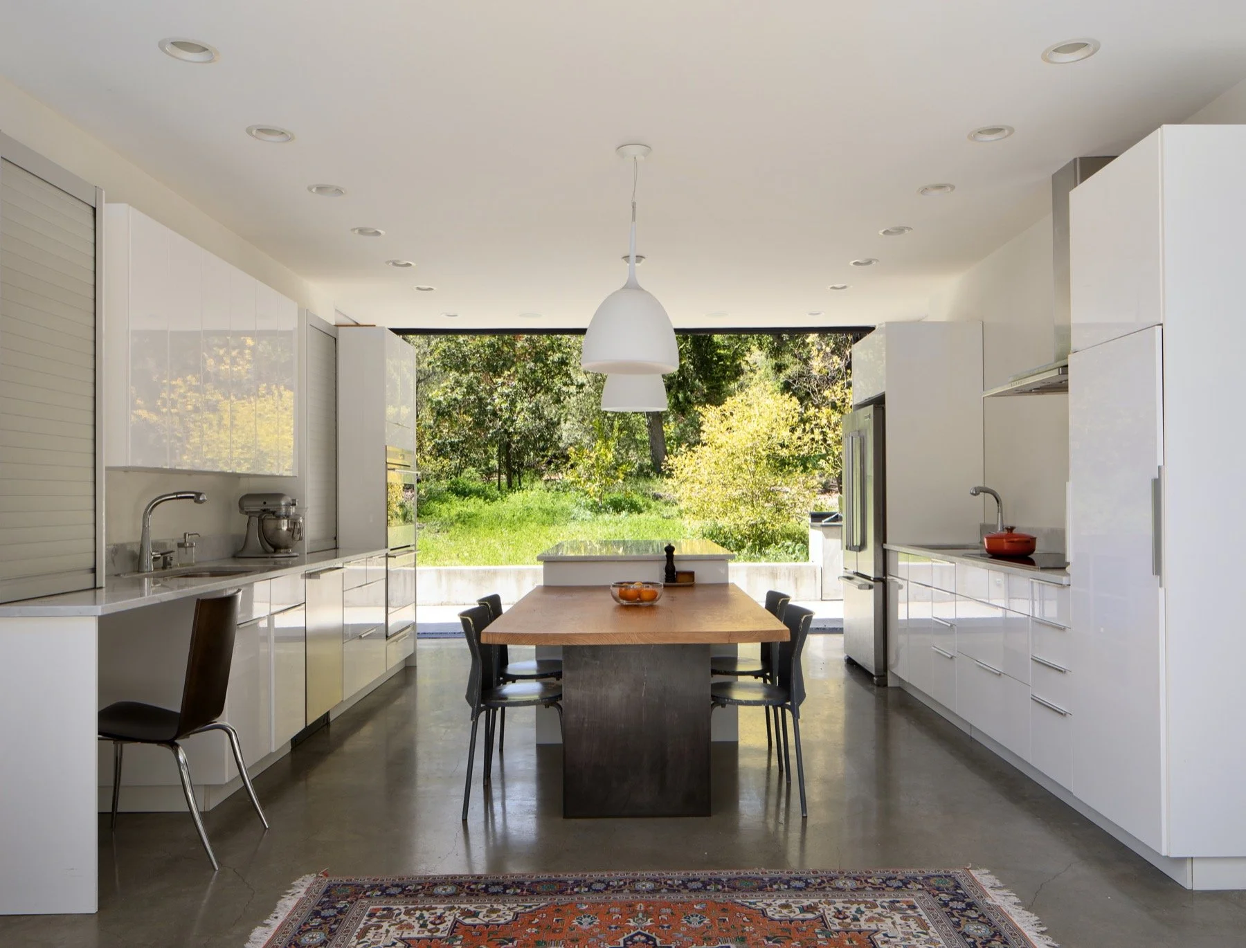  A kitchen with glossy white cabinets and a large island with a dining extension. 